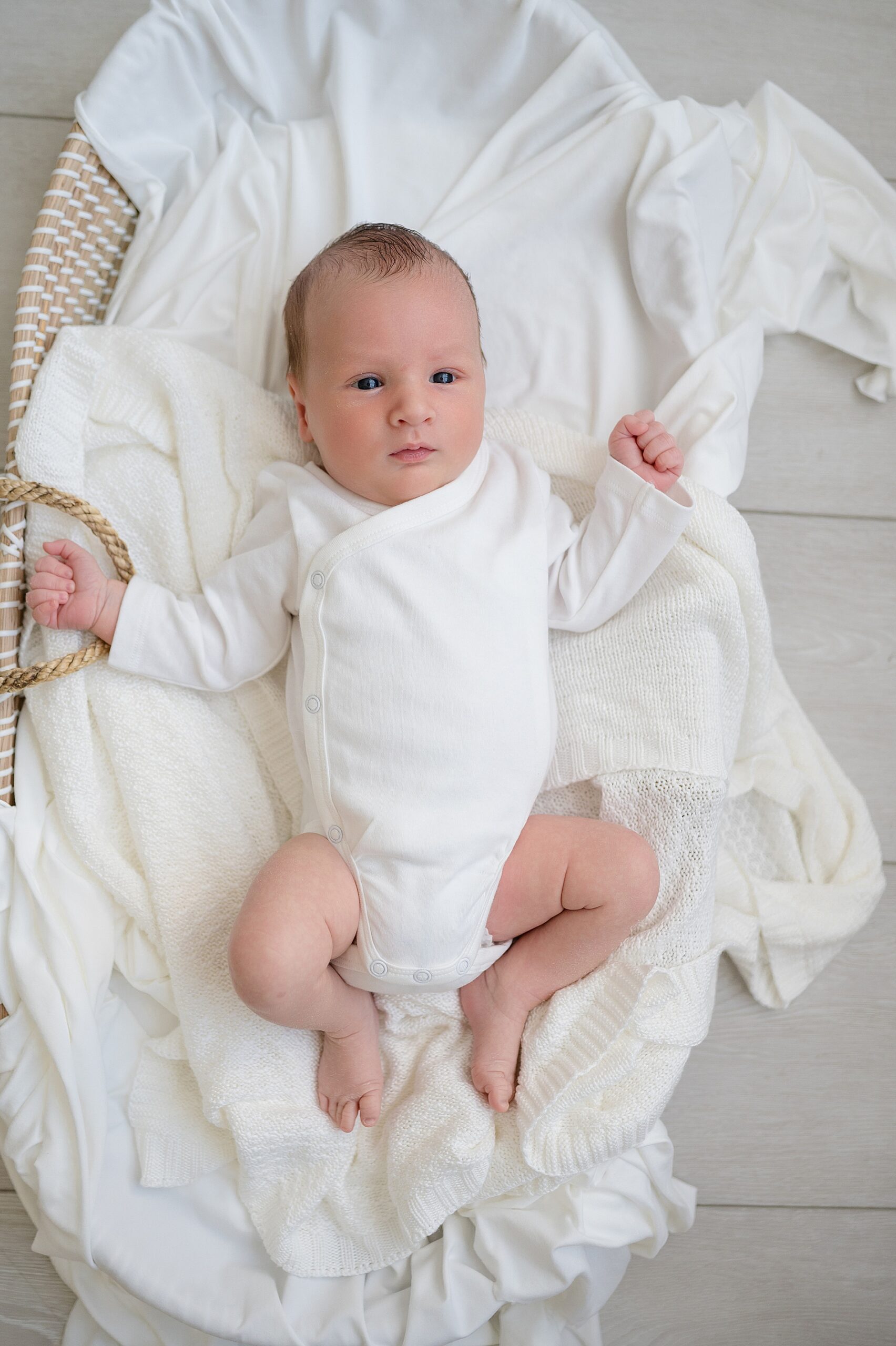 newborn in white bassinet