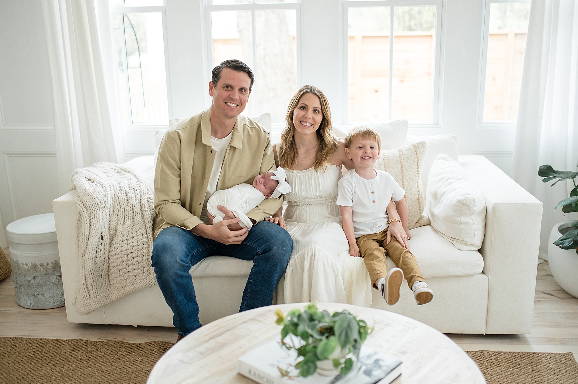 family of four sits on couch during Beverly-Harris House Newborn Session