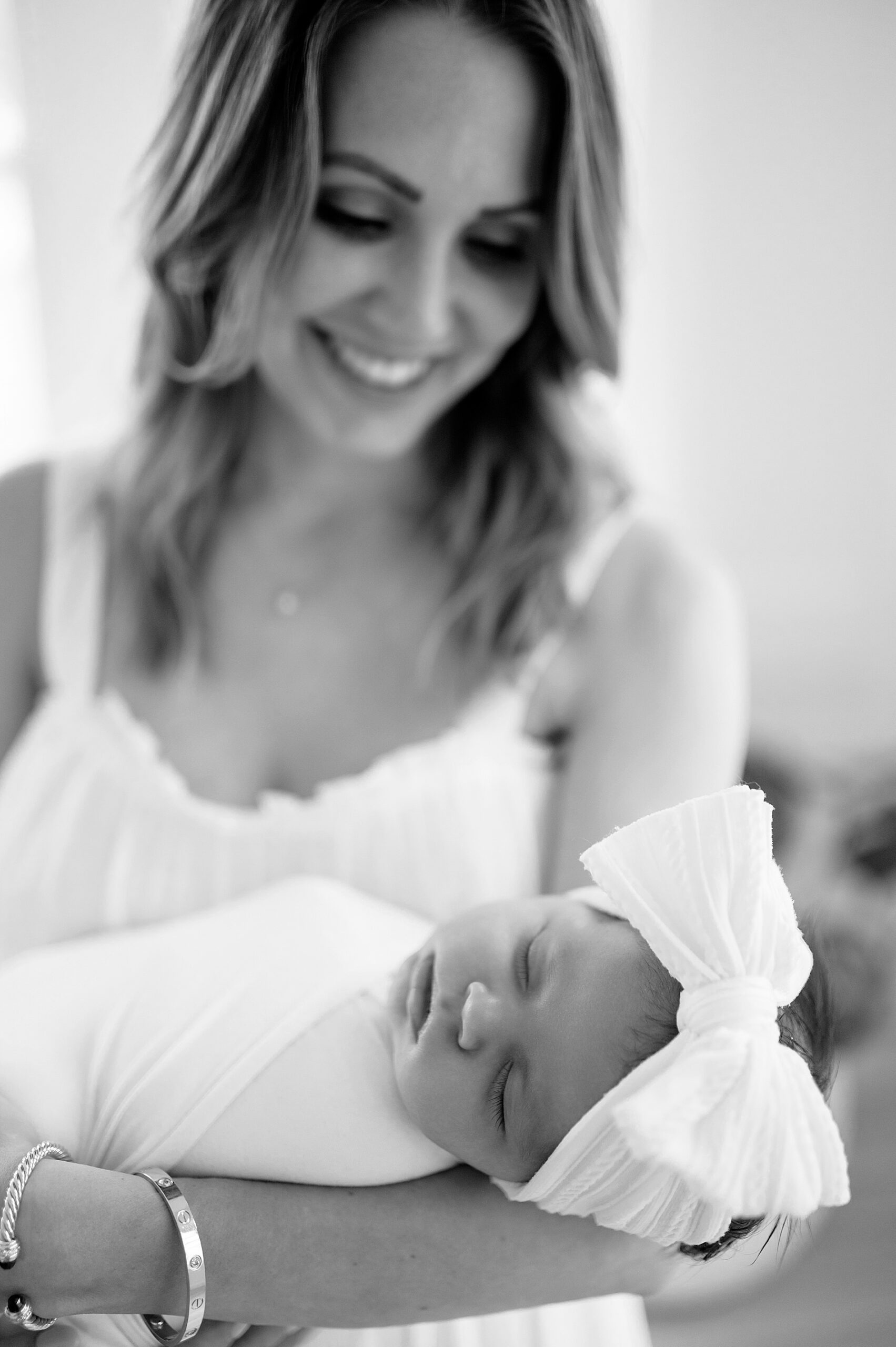 mom holds newborn girl with white bow headband 