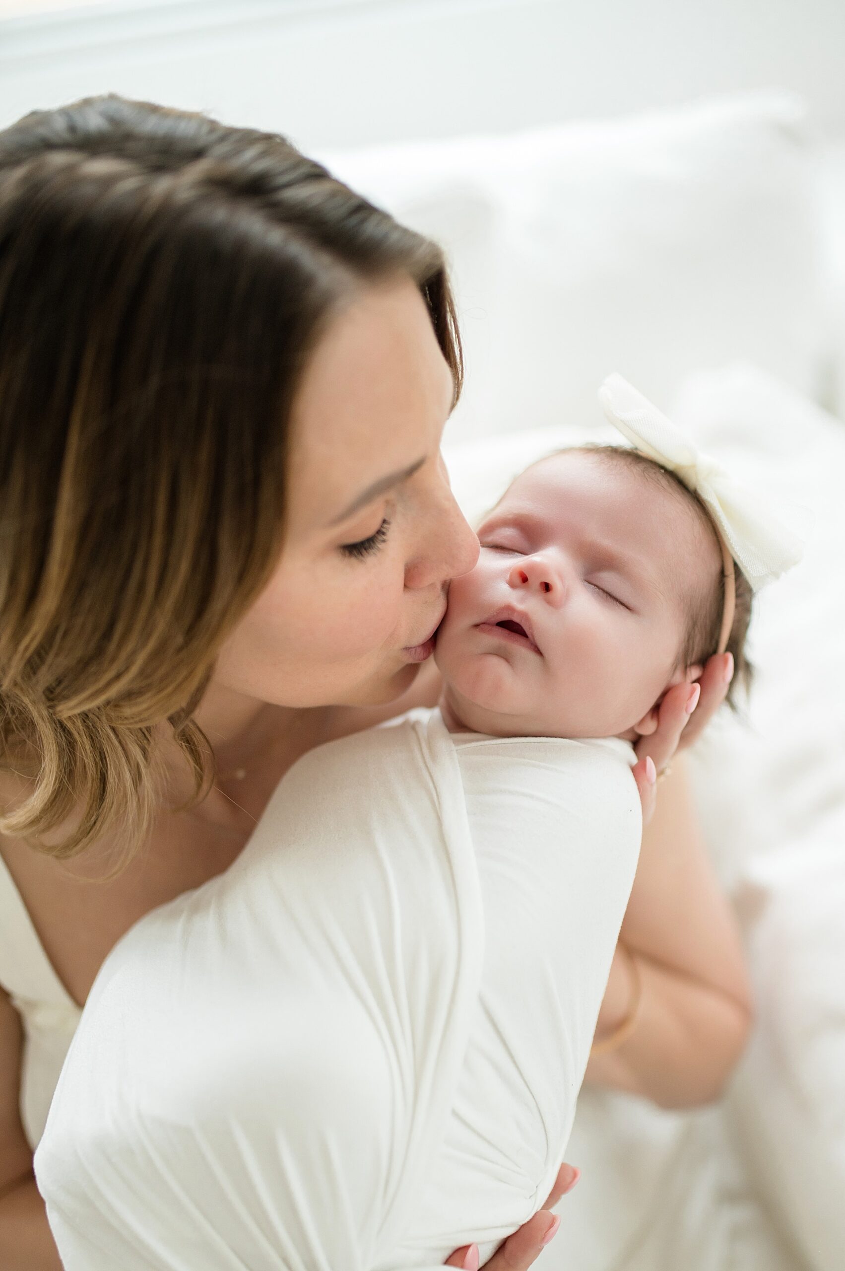 mom holds newborn up to face and kisses cheek