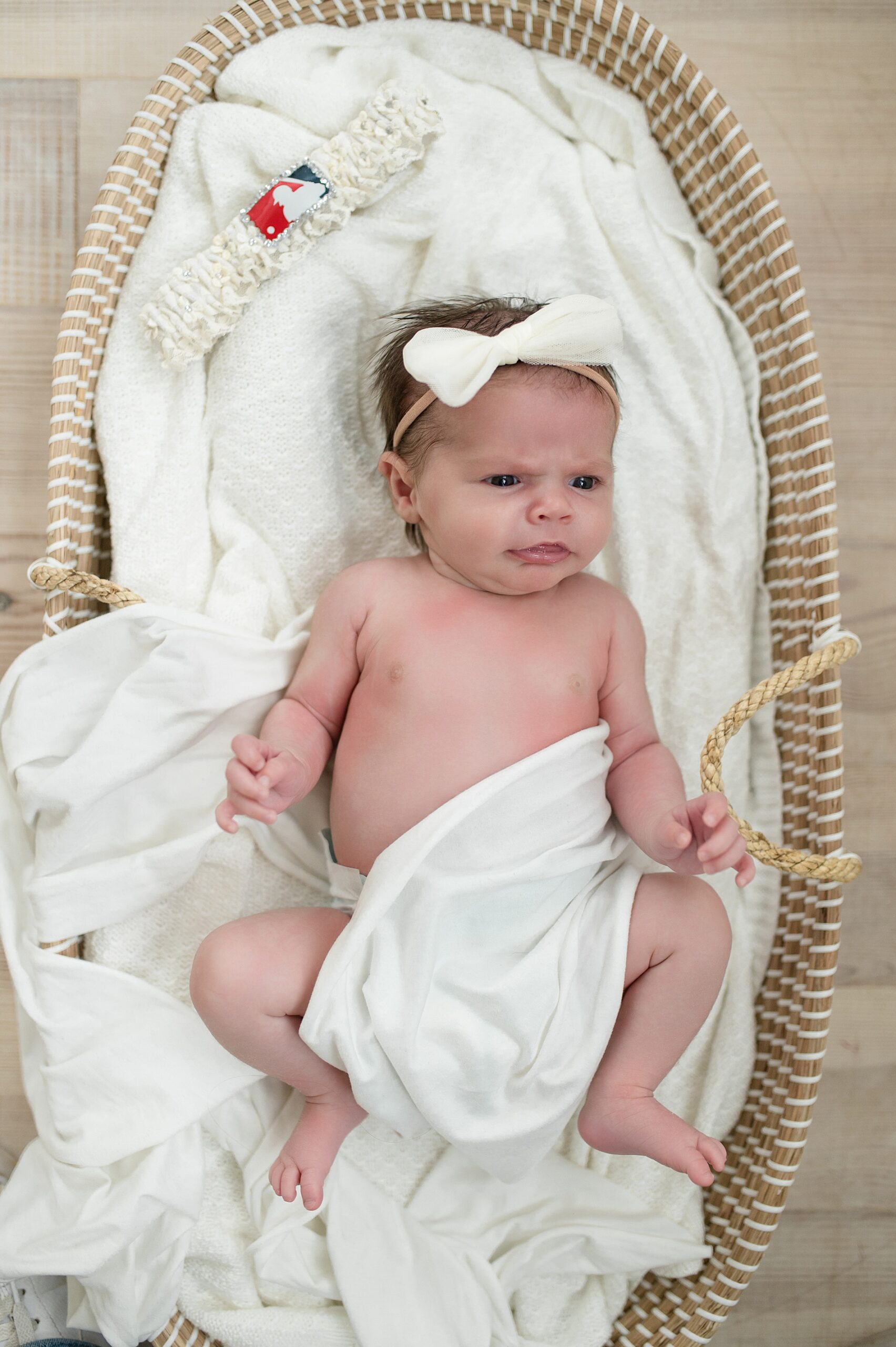 newborn girl awake in bassinet makes cute expression