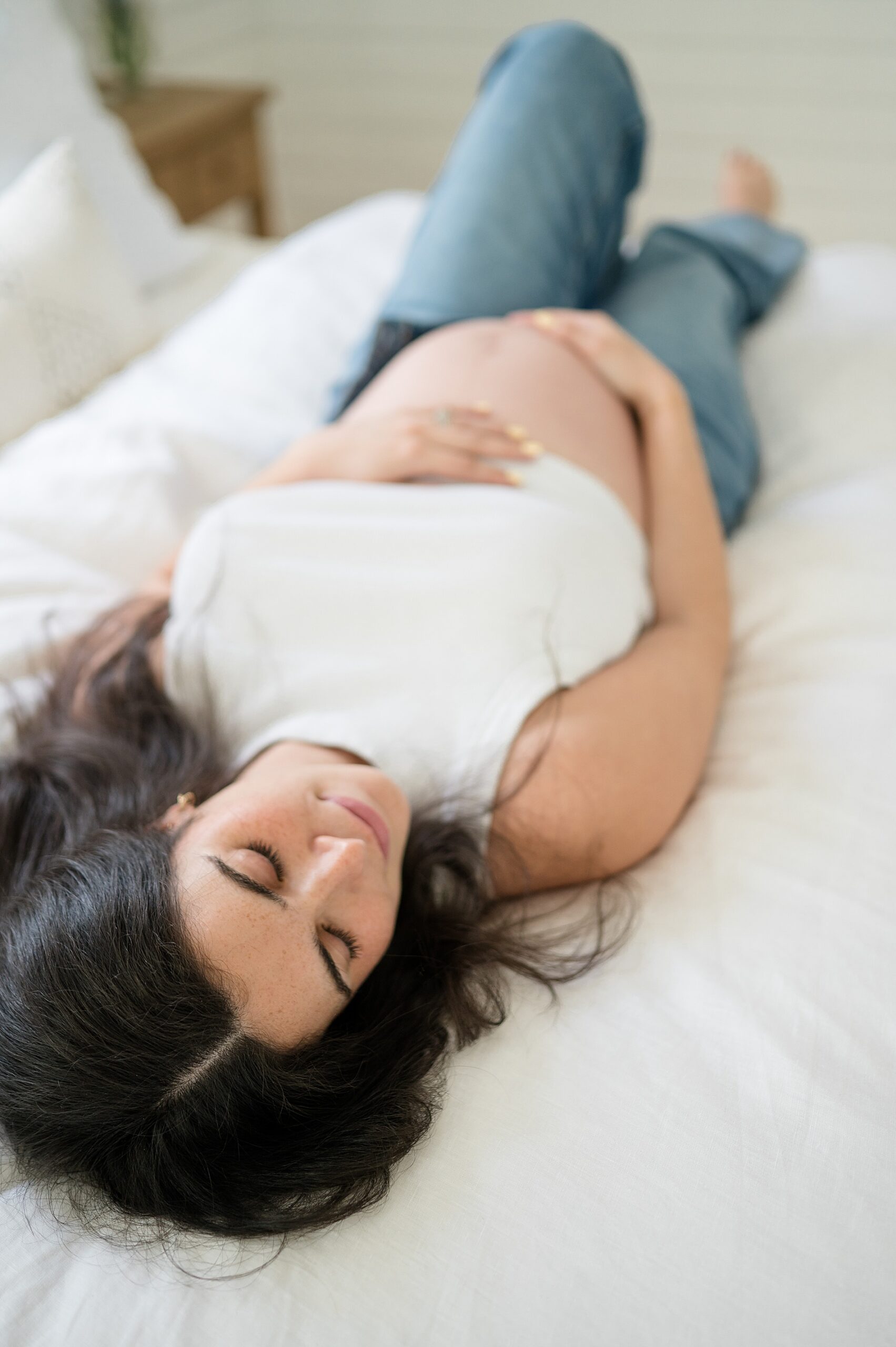 woman lays on bed during maternity session | The Best Time to Book Maternity Photos by Dallas Maternity Photographer