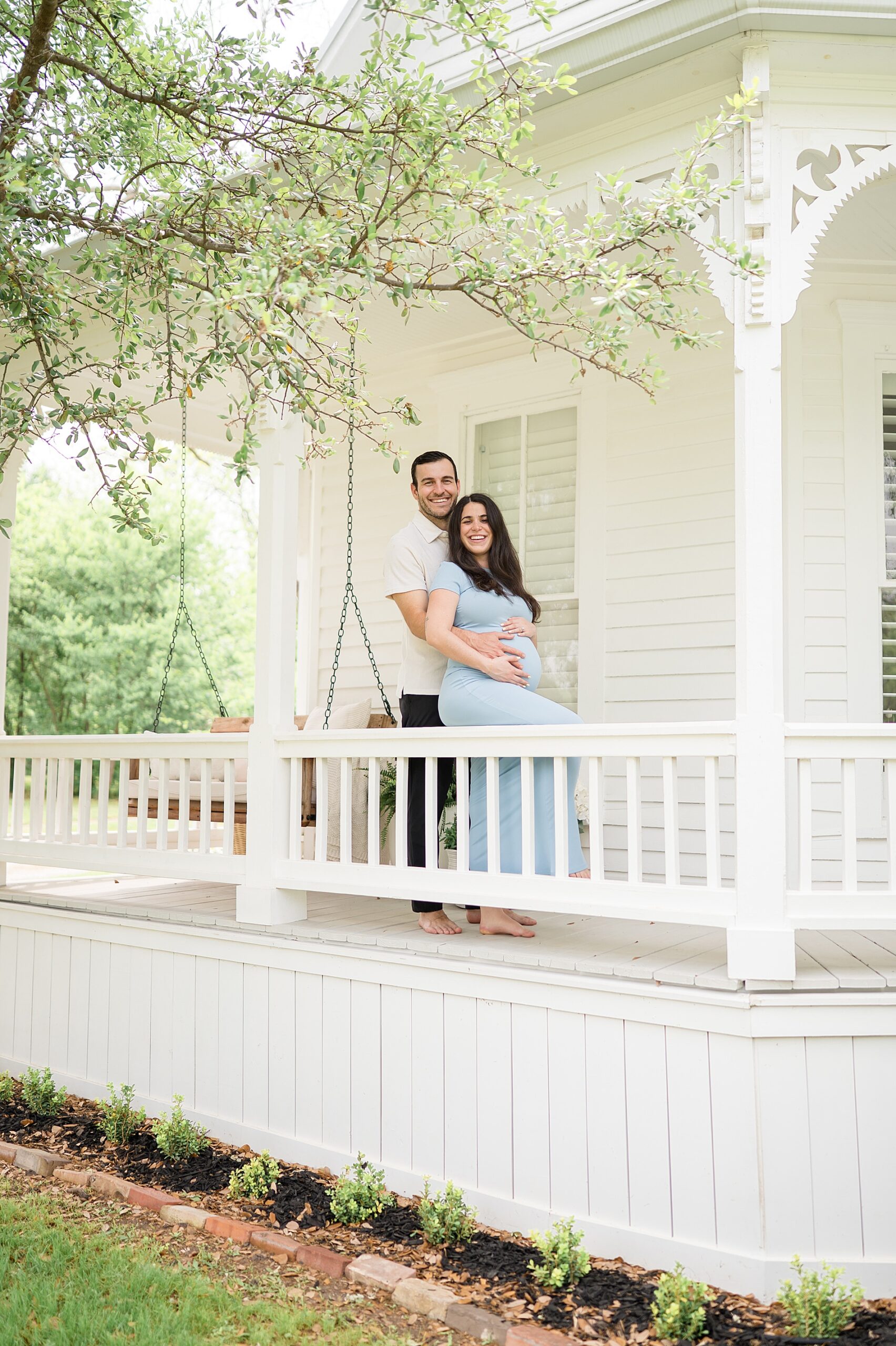 couple sit together on porch during Dallas maternity session