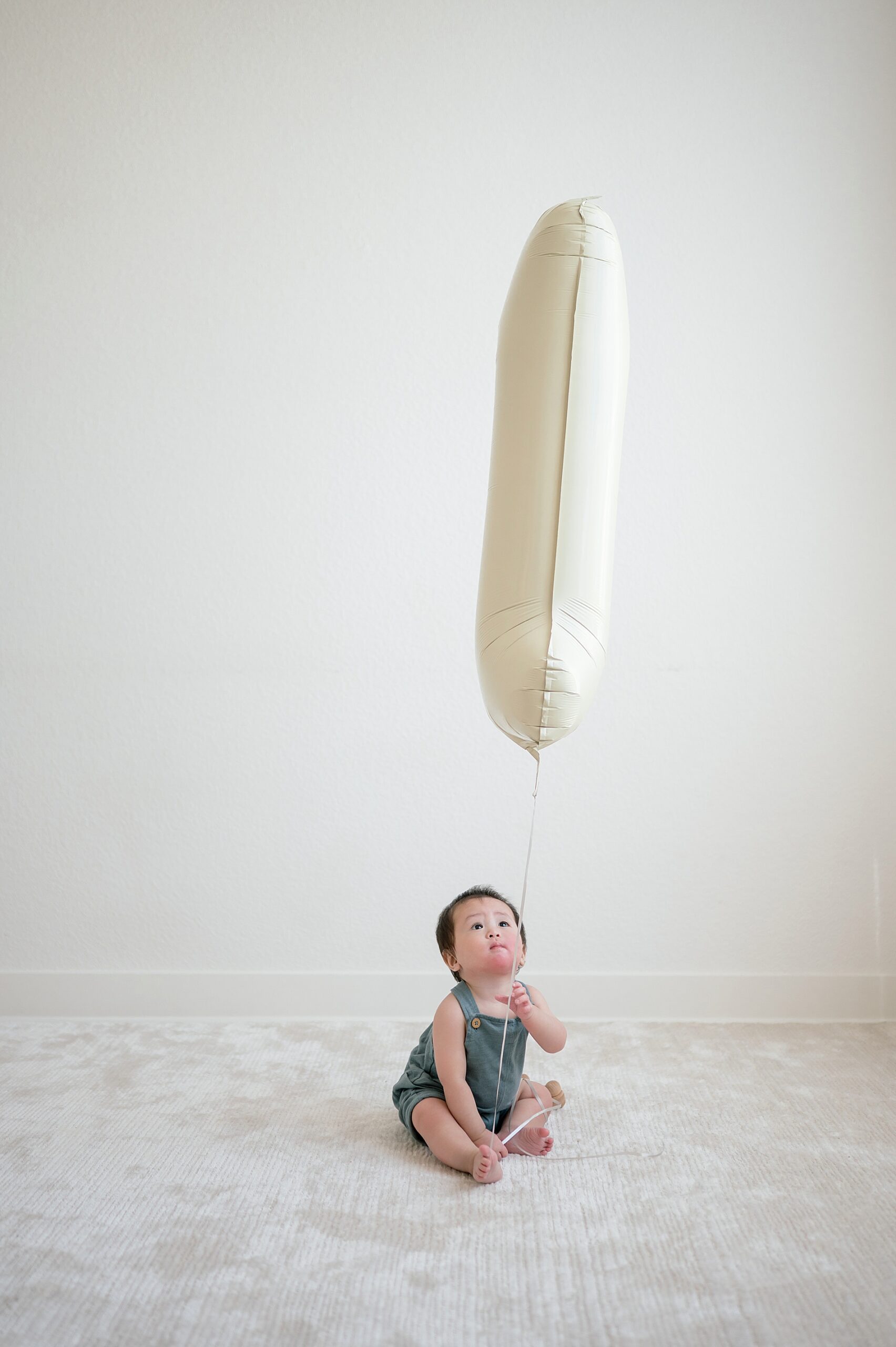 little boy holds number one balloon for first birthday