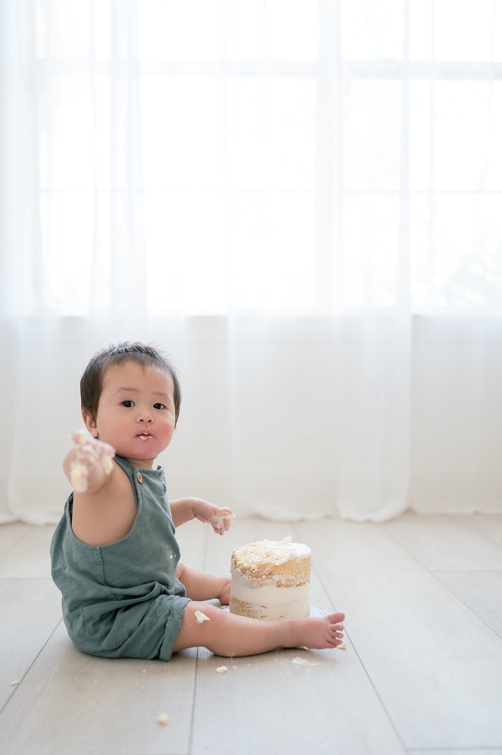 boy covered in cake and icing points at camera