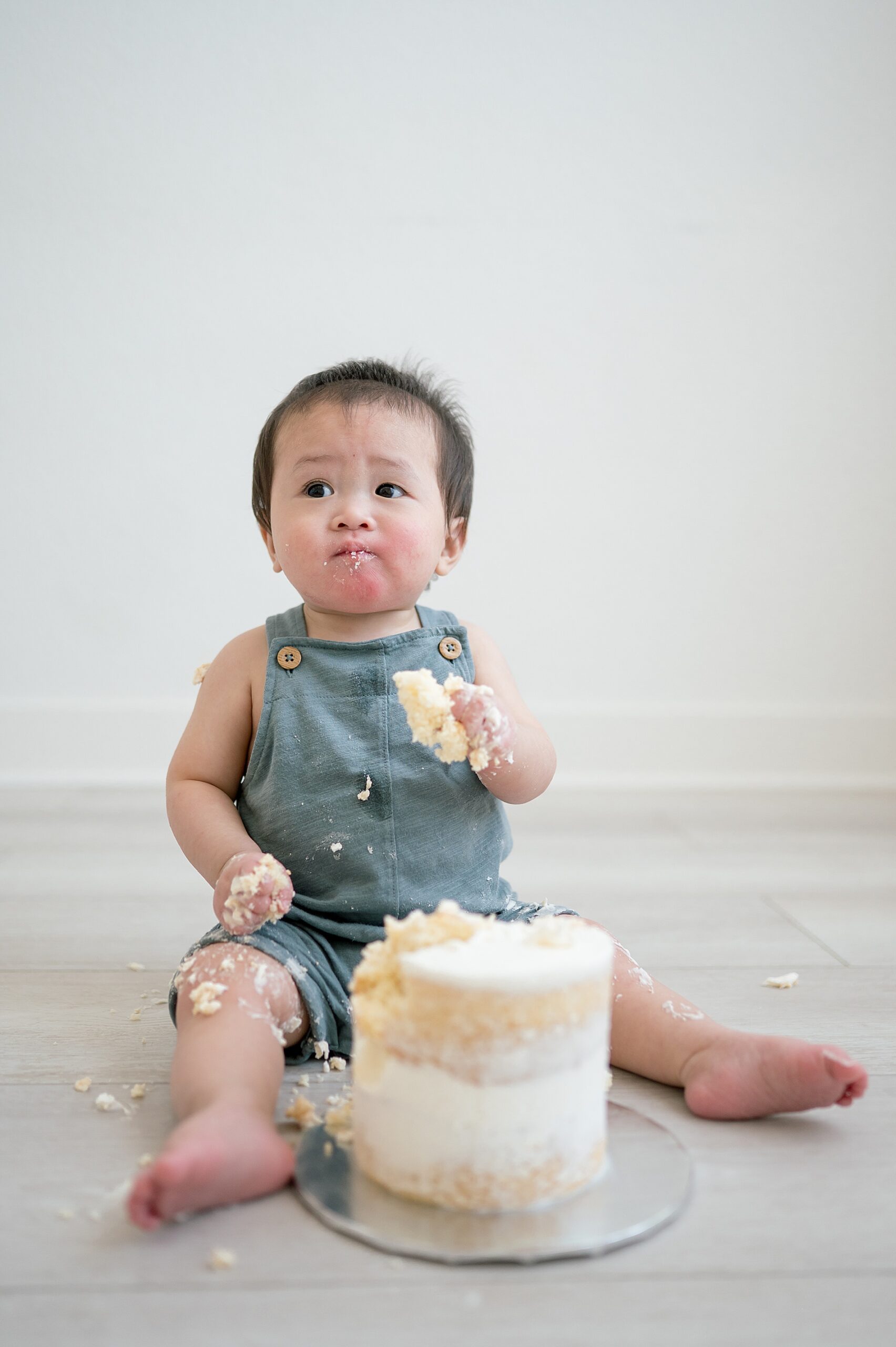 little boy eating while birthday cake during one year milestone session