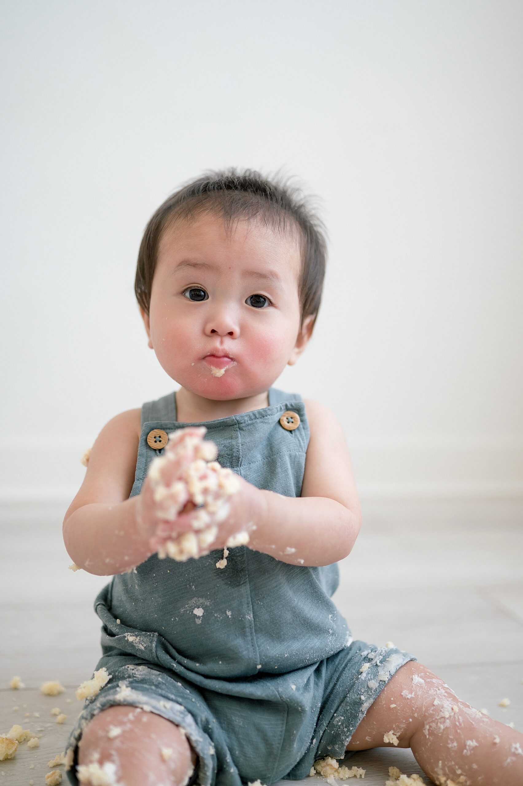 little boy with cake all over legs and arms from cake smash session