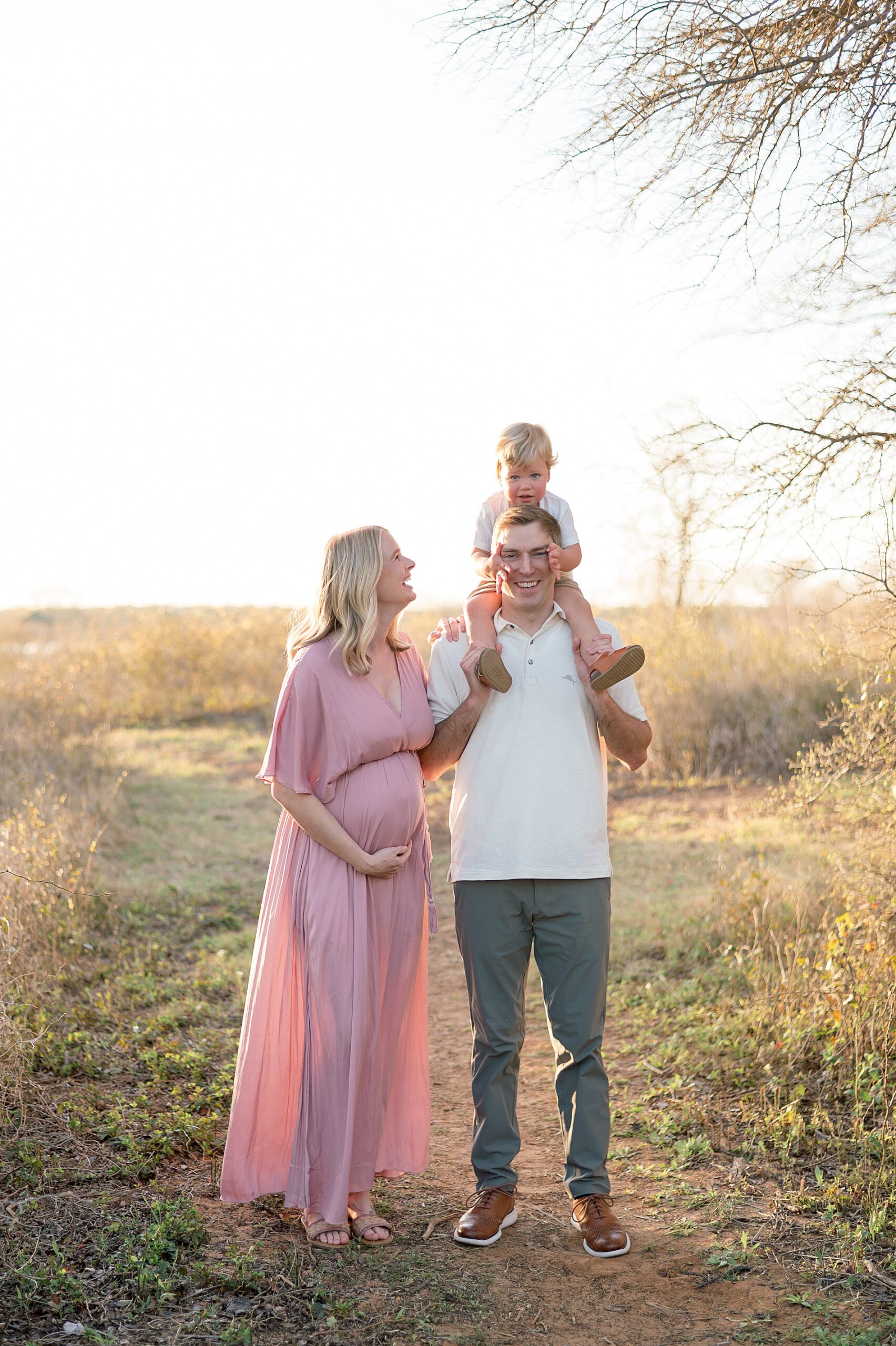 expectant mom in flowy pink dress with husband and son