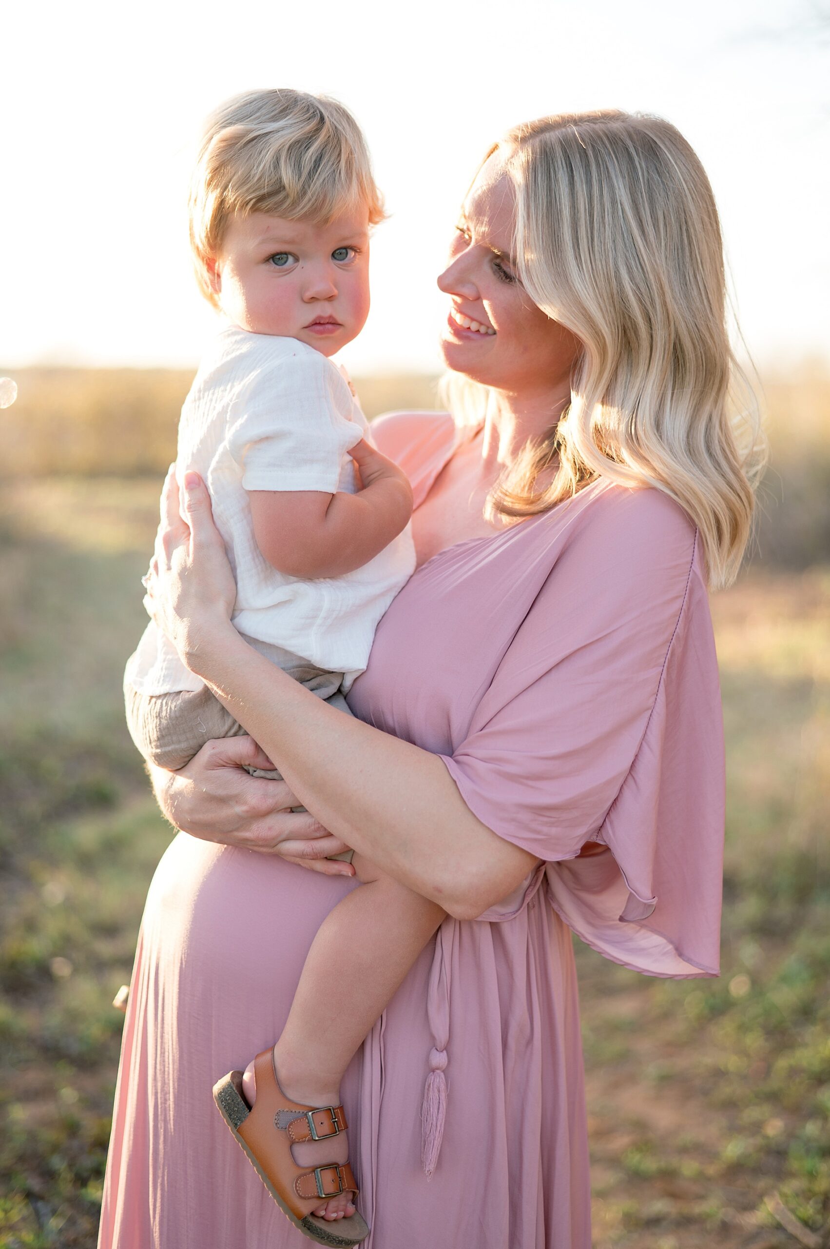 mom in pink dress holds oldest son