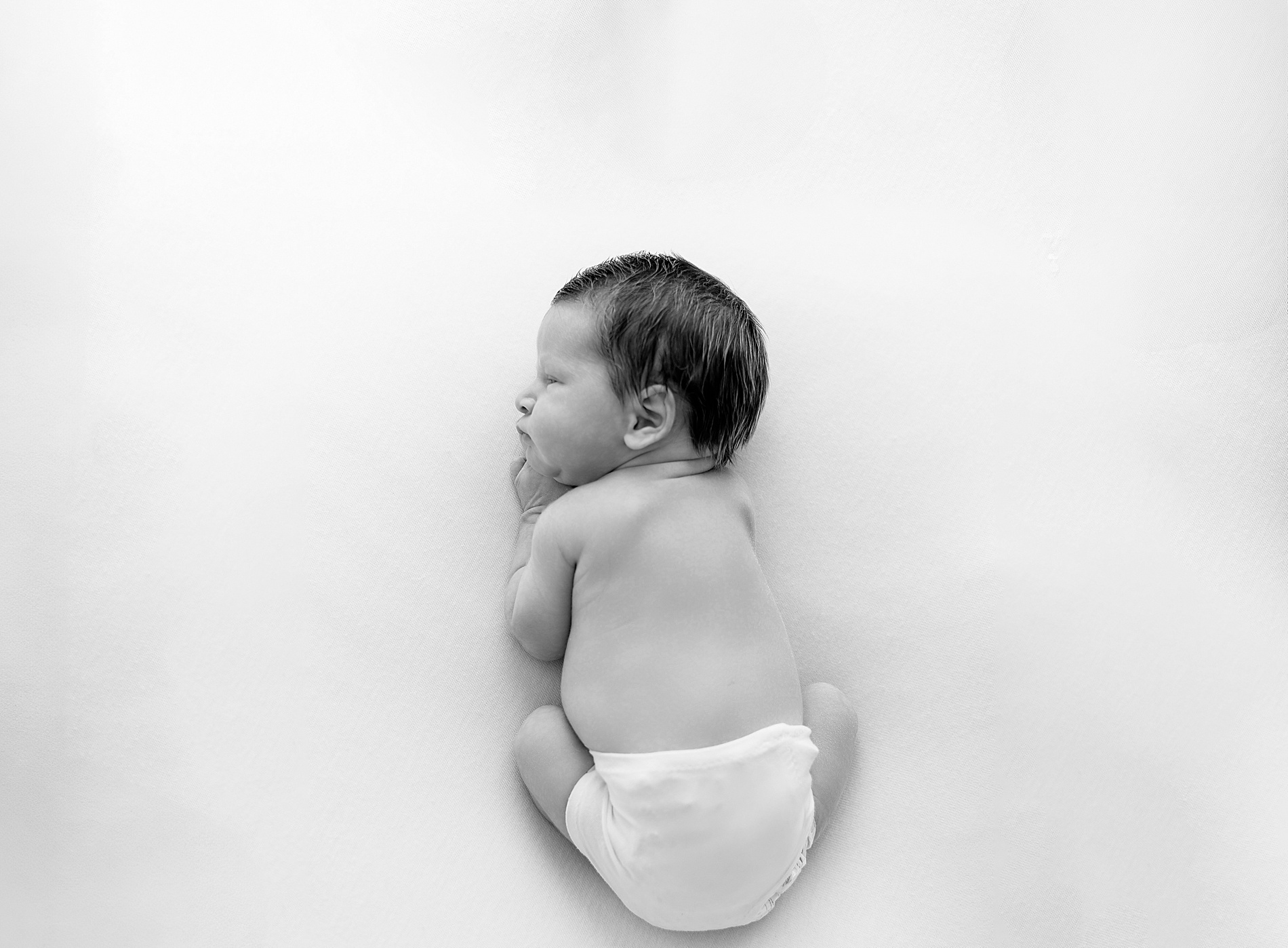 newborn boy curled up
