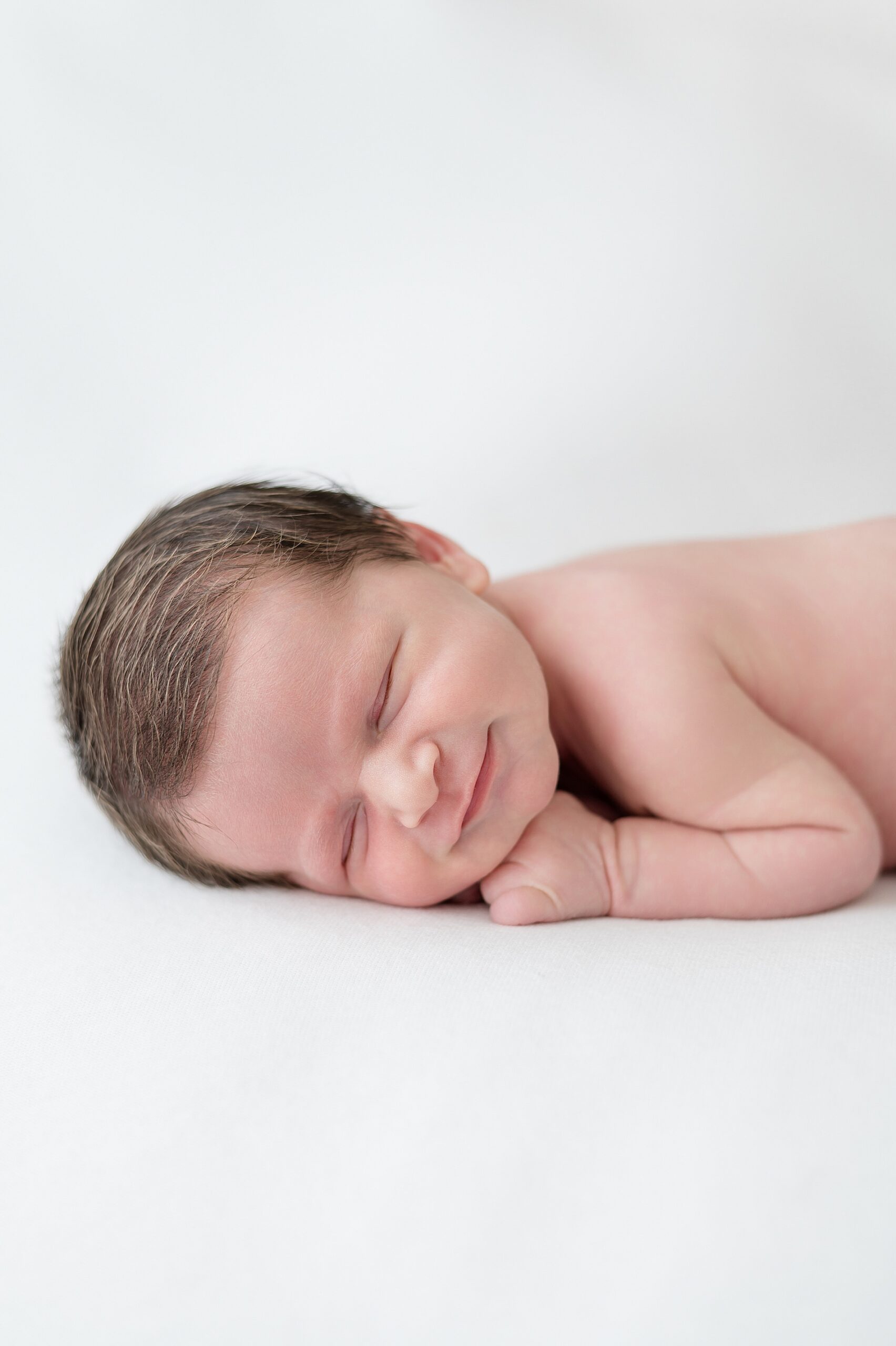 sleepy newborn boy smiles as he sleeps