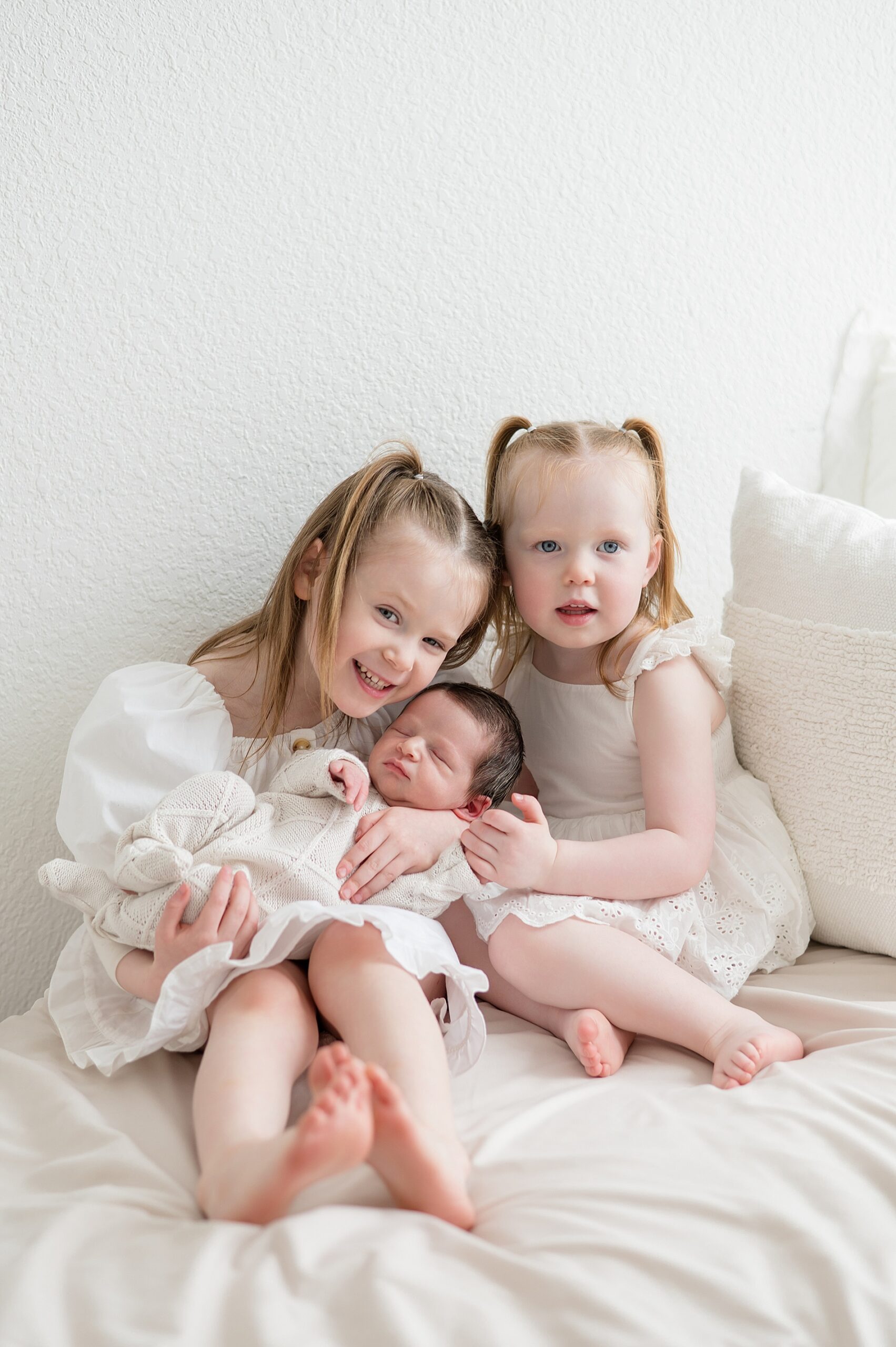 big sisters hold newborn brother during Dallas Studio Newborn and Family Session