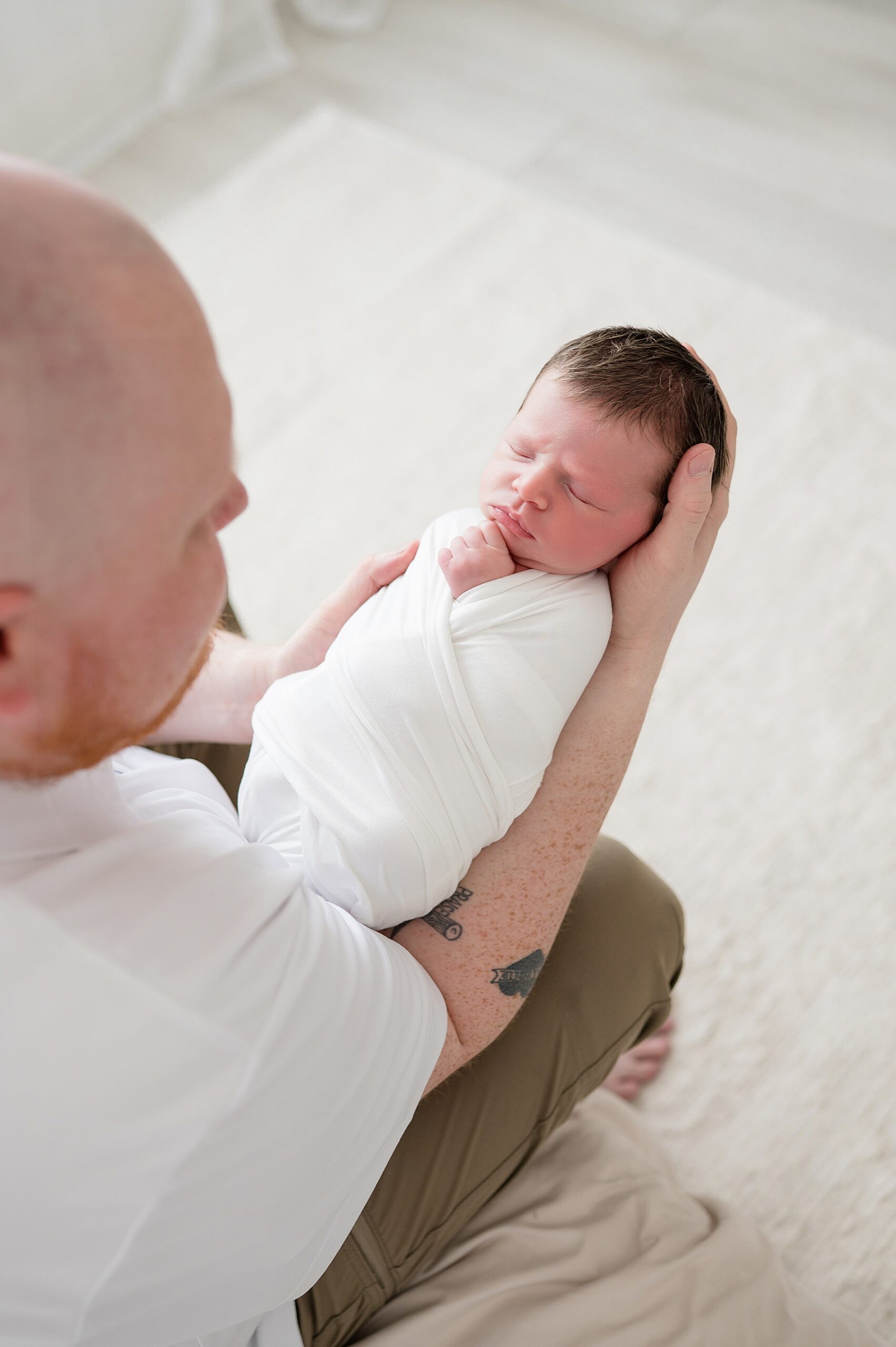 dad holds newborn boy in arms and looks down at him