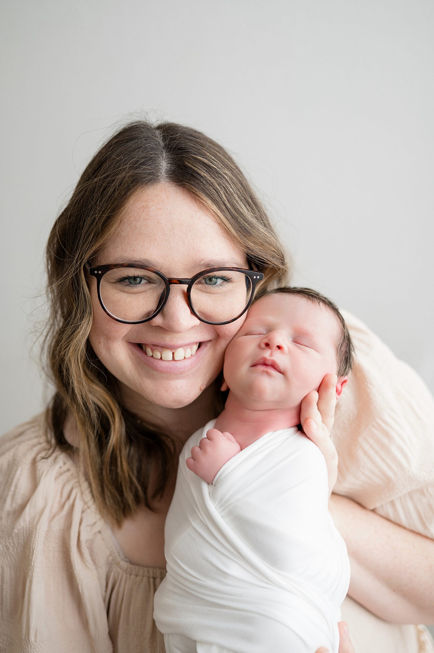 mom holds newborn boy by her face
