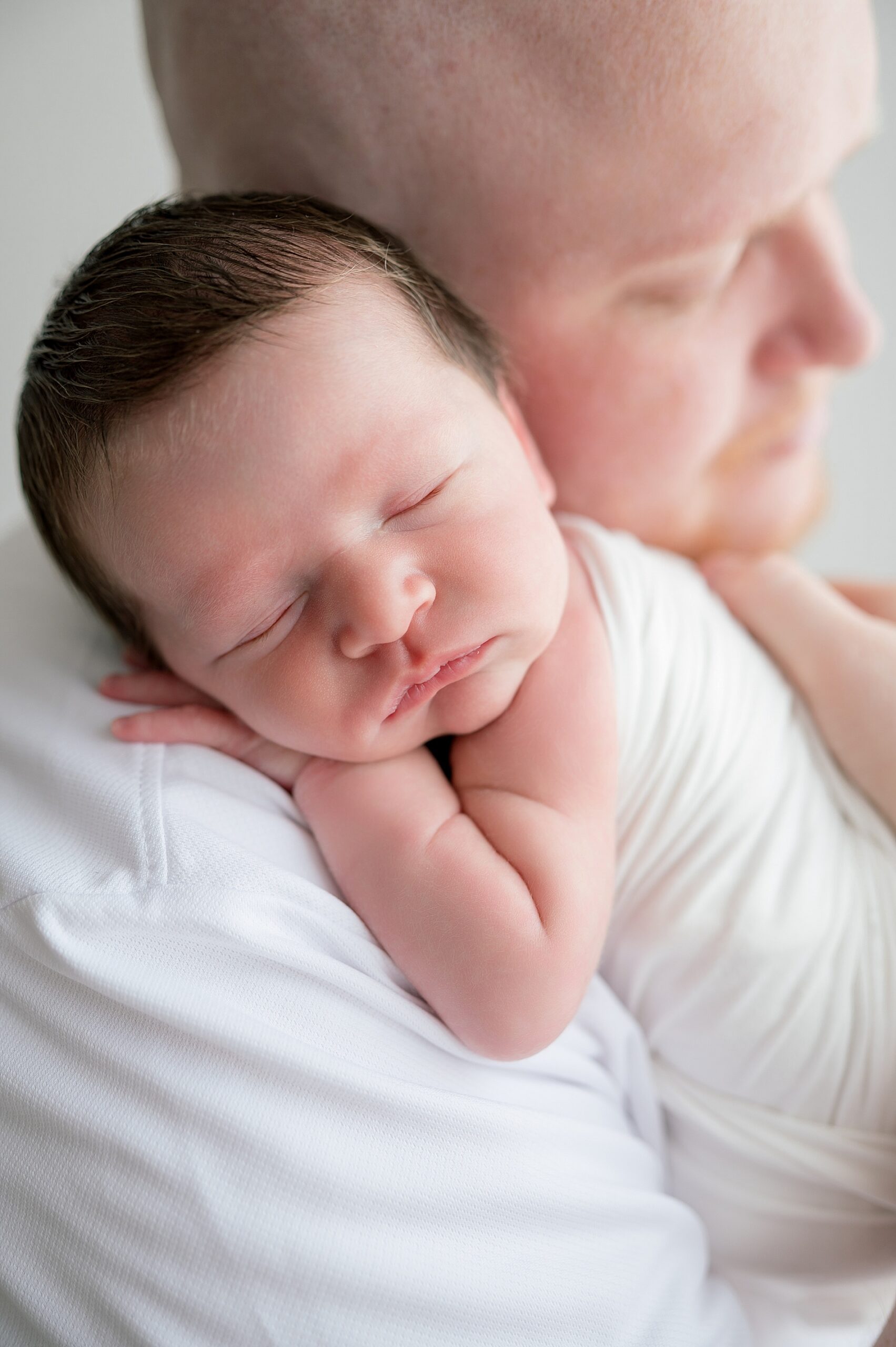 newborn boy sleeps on father's shoulder