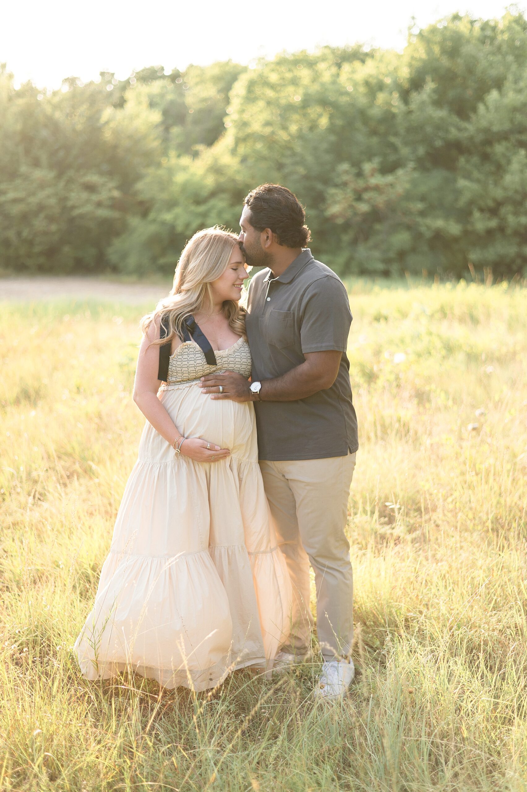 man kisses his wife's head with hand on baby bump 