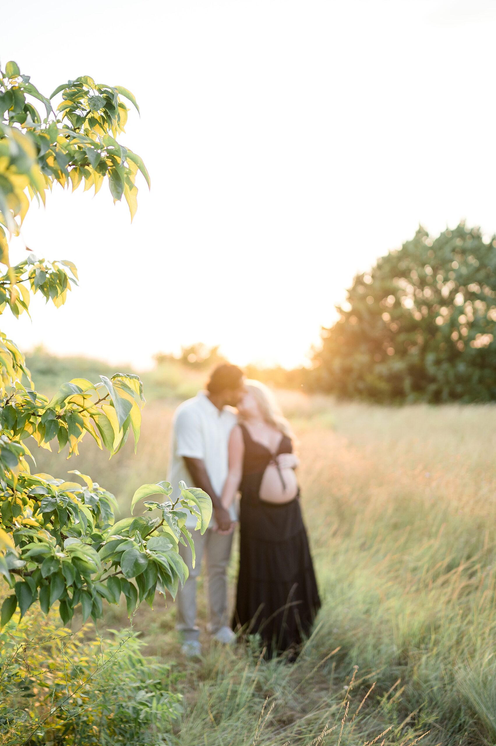 couple kiss during golden hour maternity session
