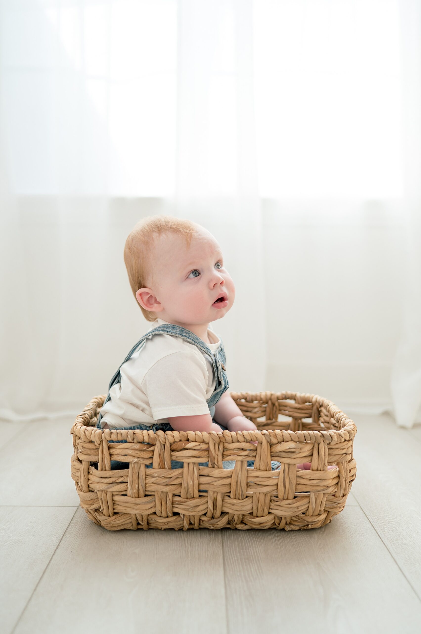 one year old boy sits in basket during milestone portraits in TX studio 