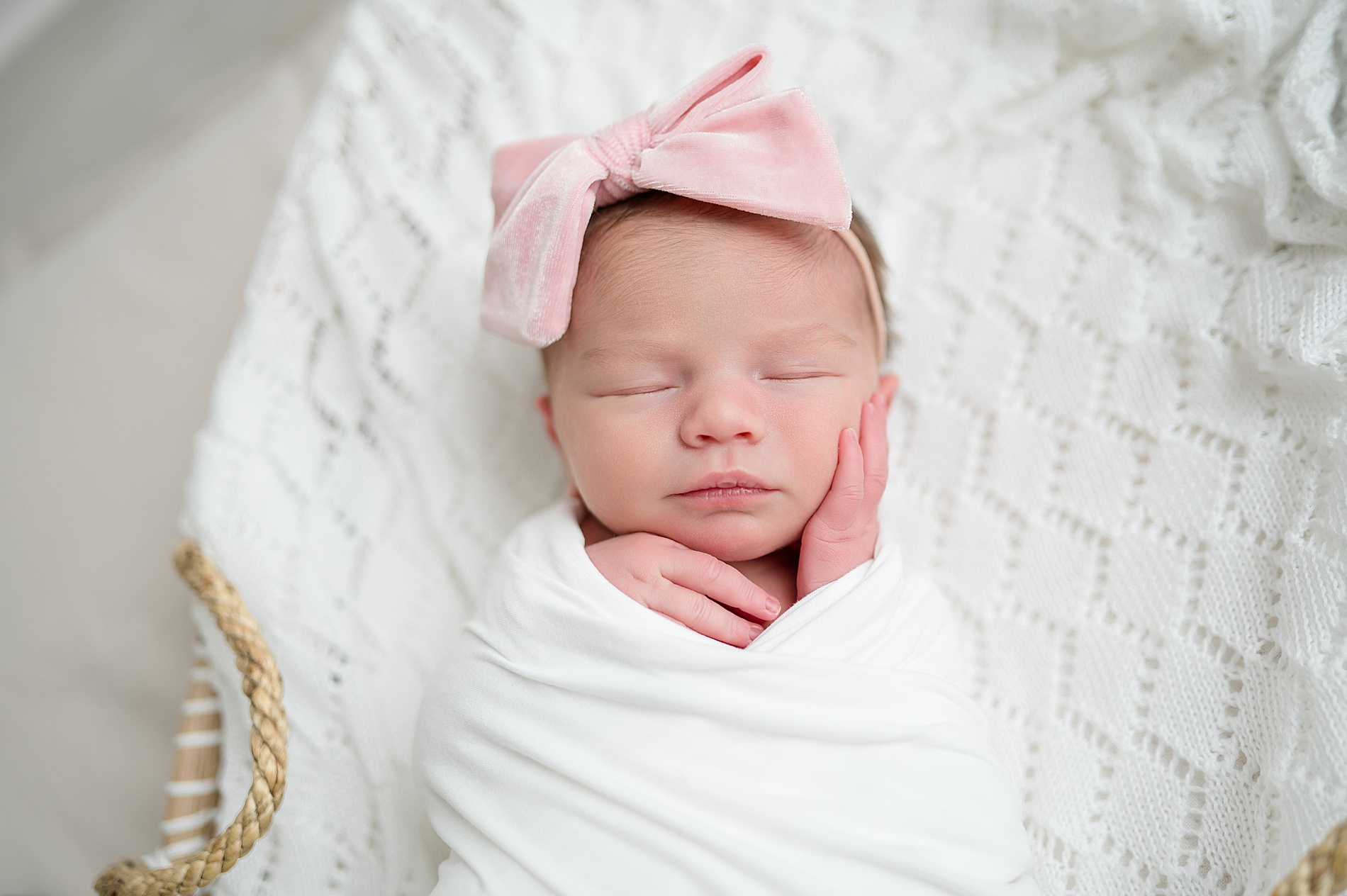 little girl swaddled in white blanket wearing pink bow during Studio Newborn Photography