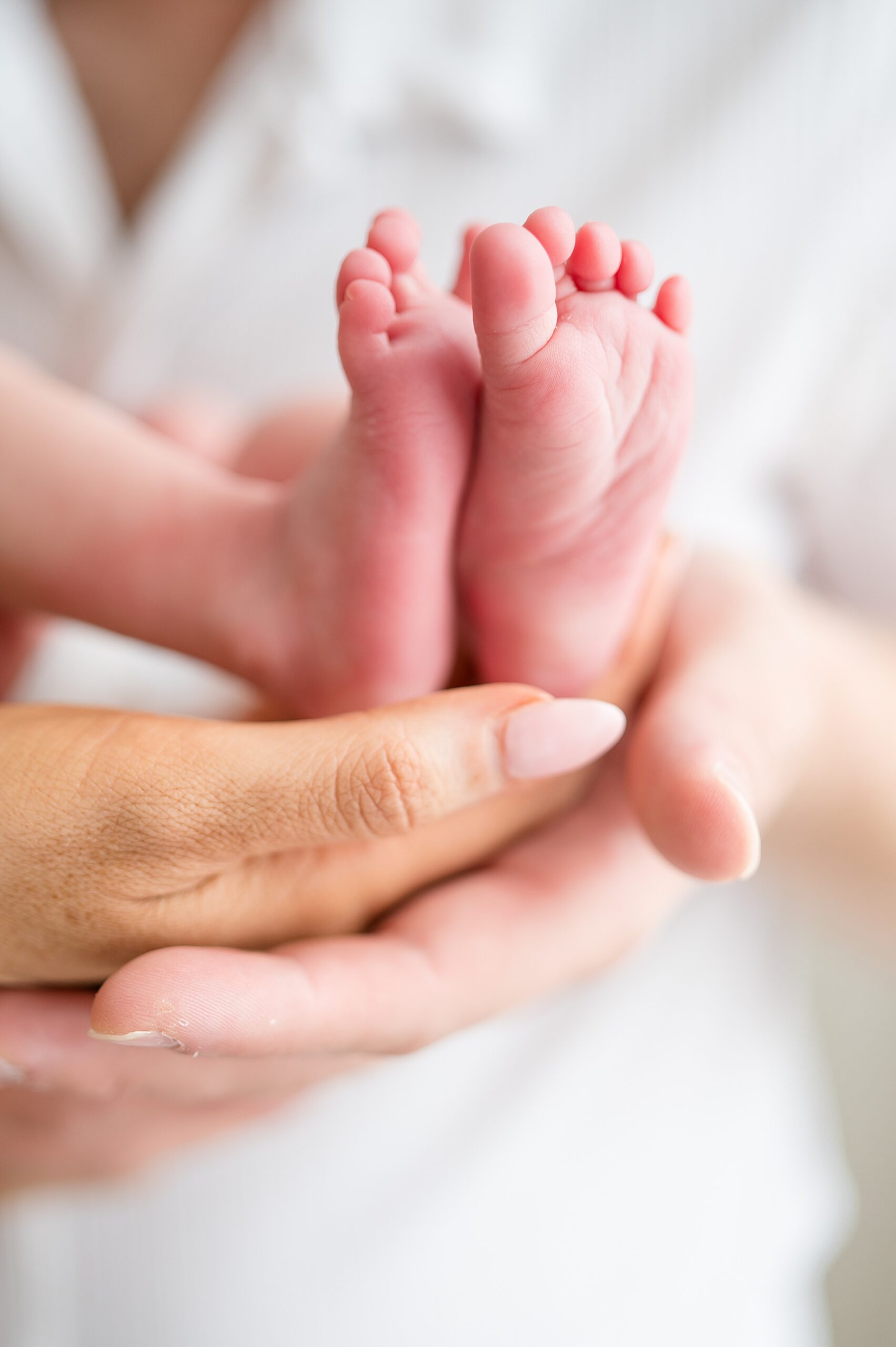 tiny toes and feet of newborn cradled in parents hands | Studio Newborn Photography is The Perfect Choice to Capture Your Baby’s Portraits