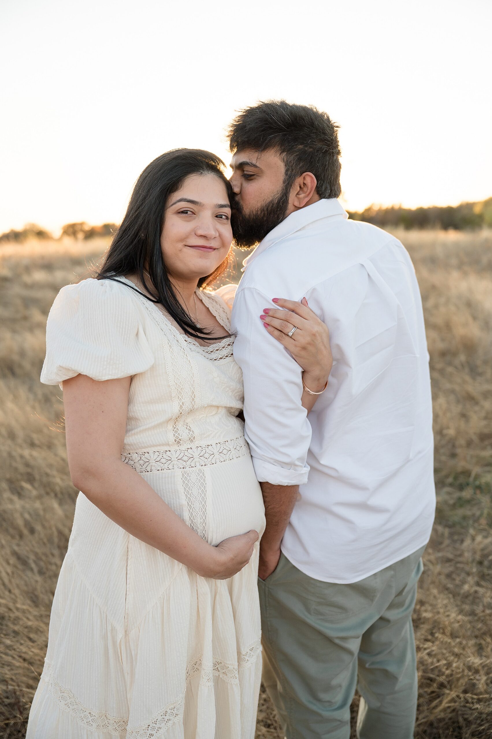 man kisses his wife's head 