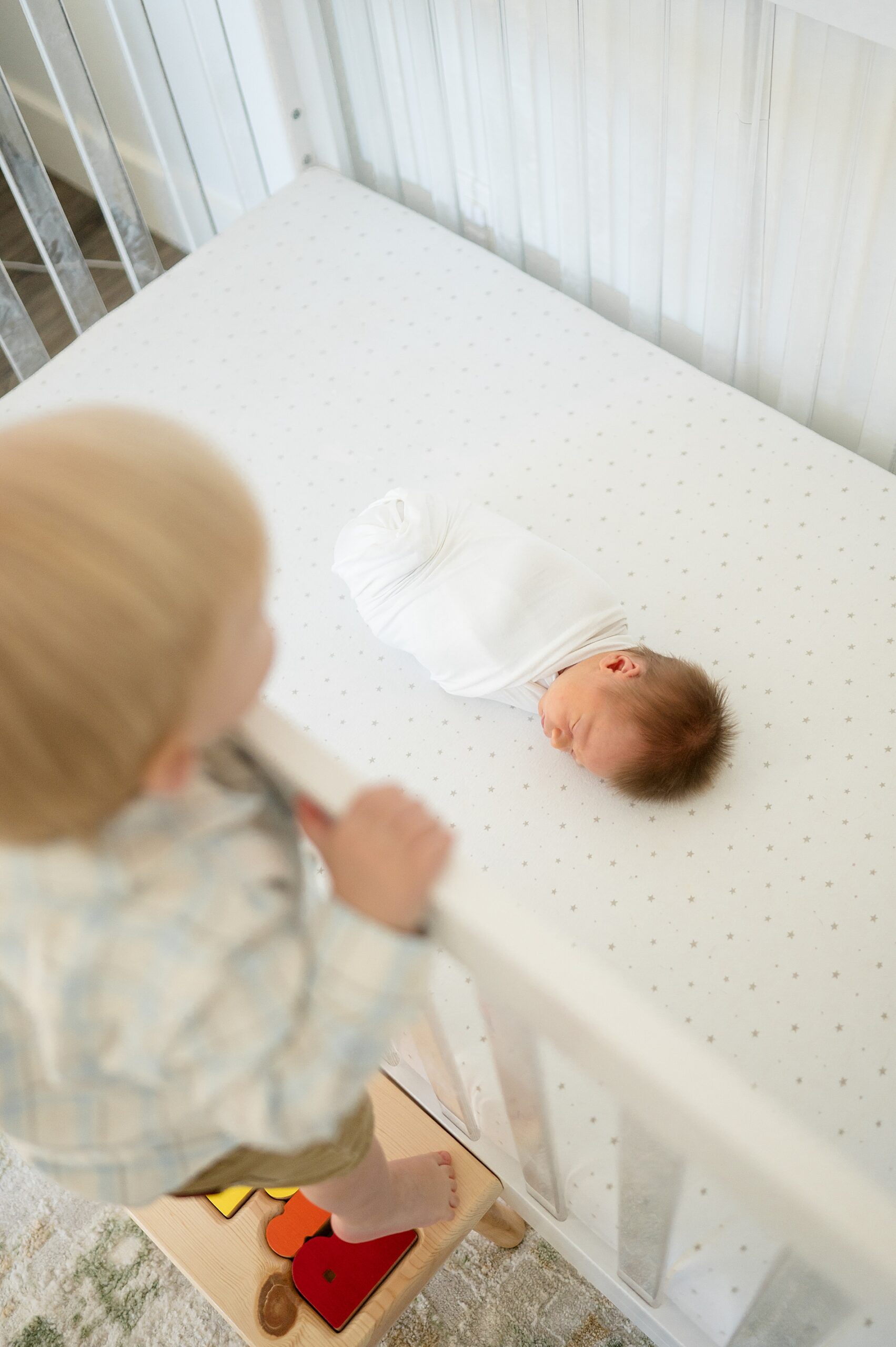 big brother peeks at newborn brother sleeping