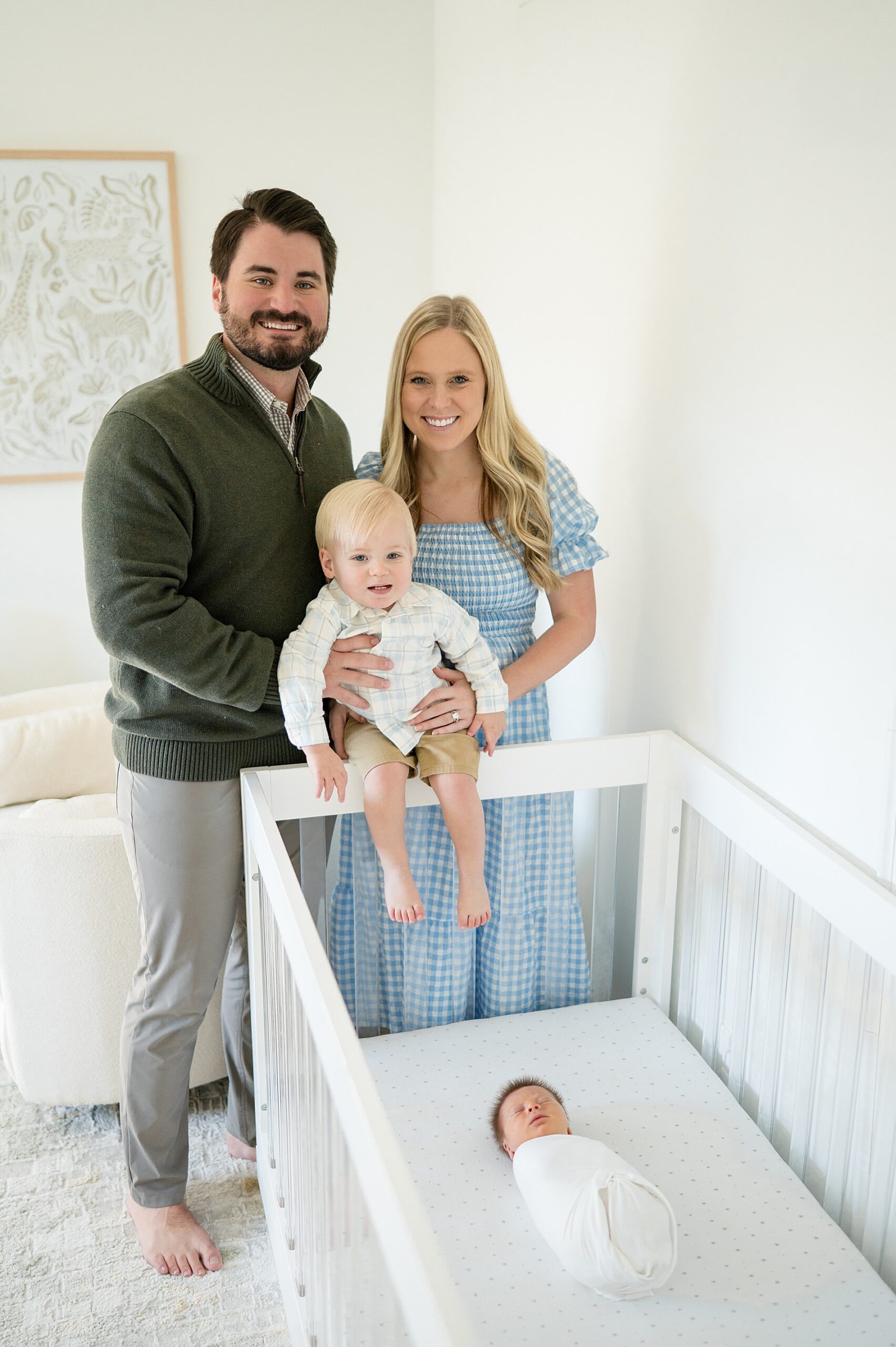 parents hold older son by crib as newborn brother sleeps