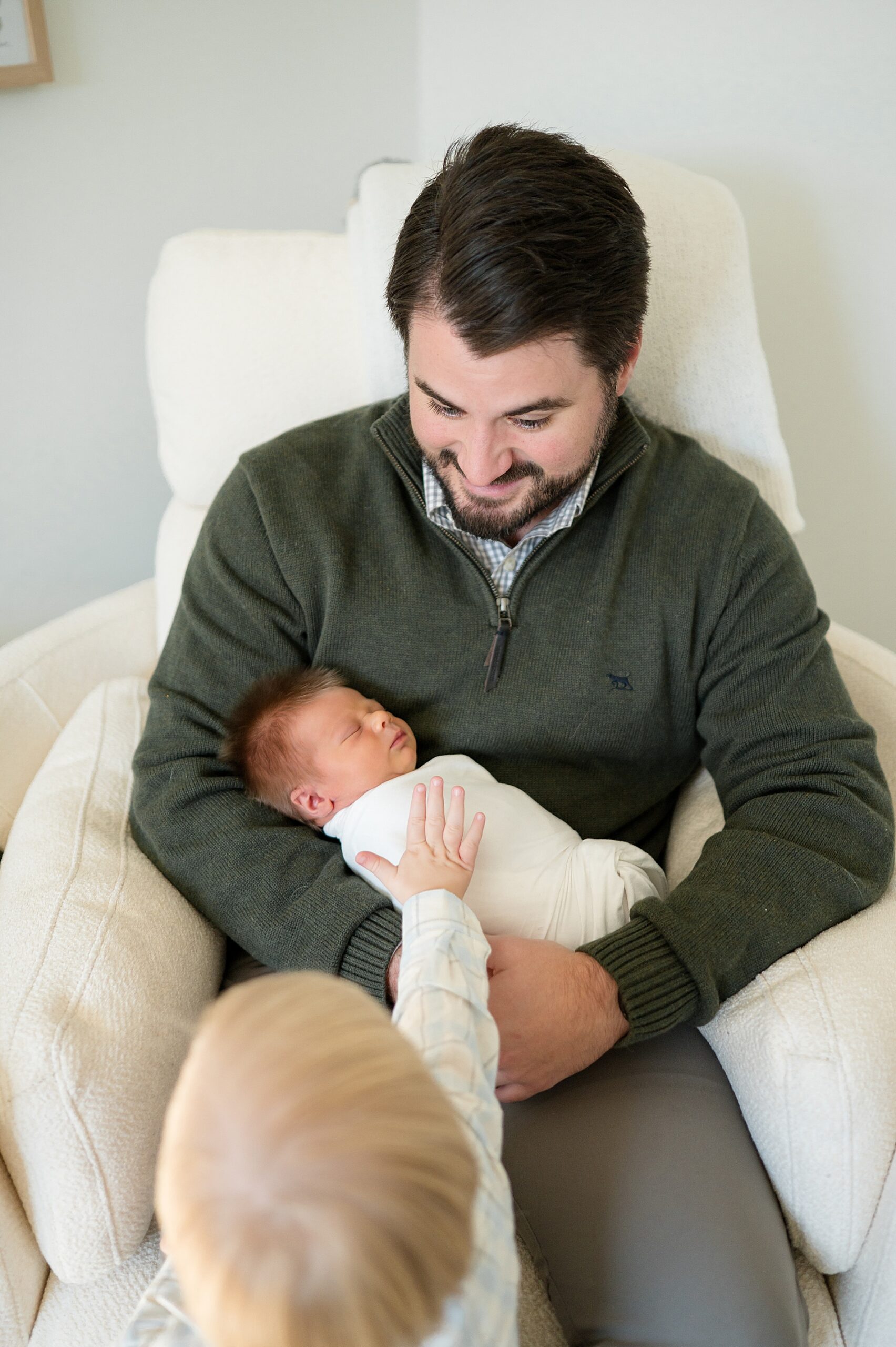 dad holding newborn as big brother pats him gently. Including Siblings in Newborn Photos | Letting Kids Be Kids