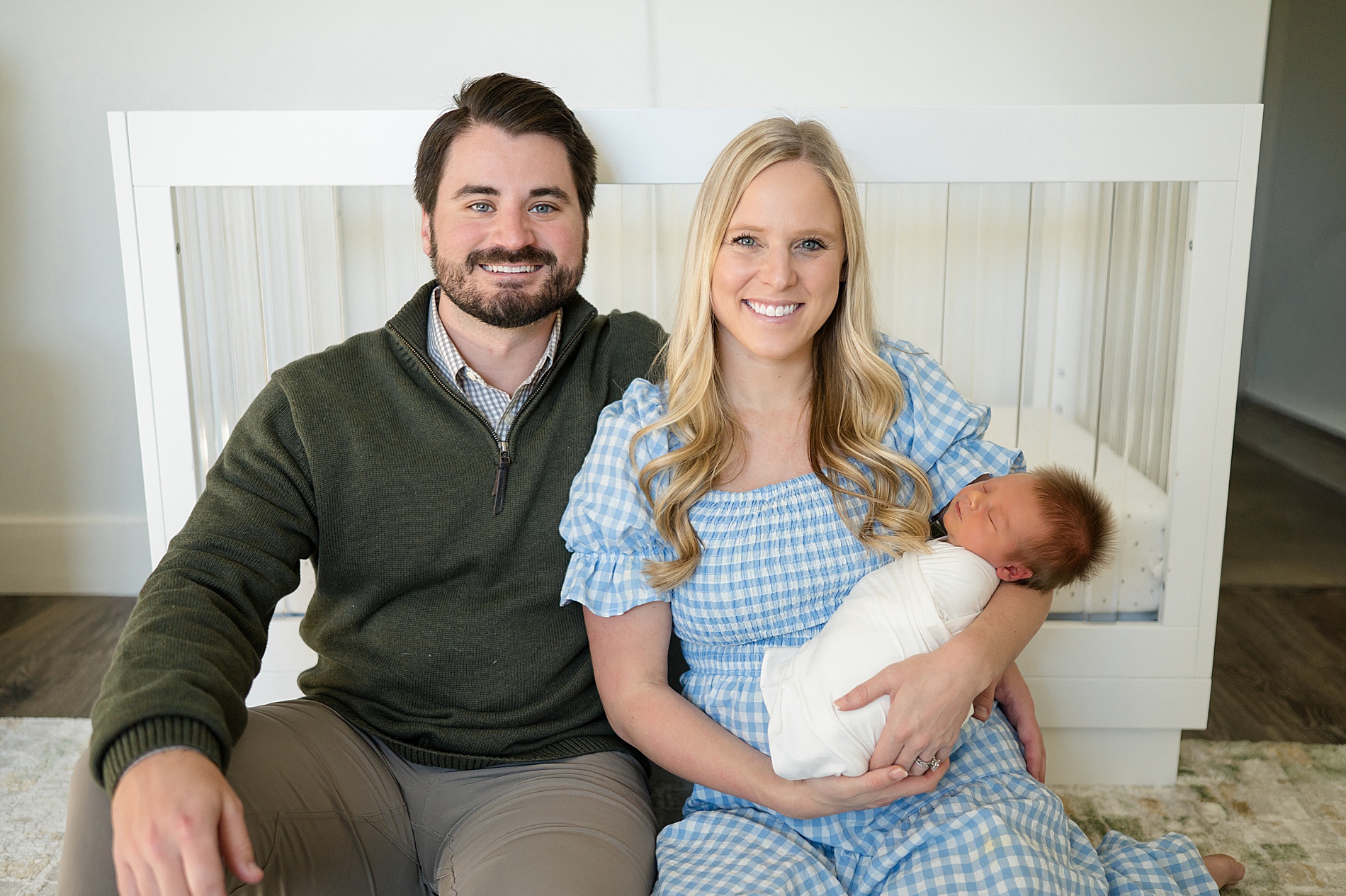 parents sit on floor of nursery holding newborn 