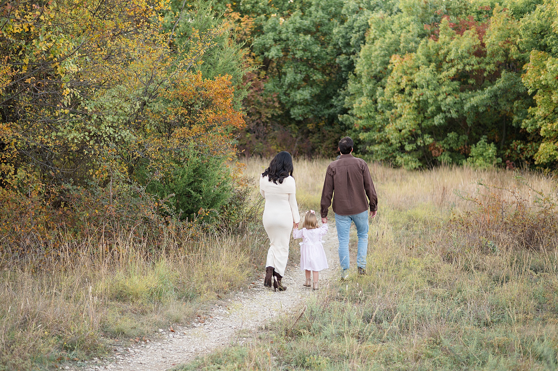 family holds hands as they walk down trail 