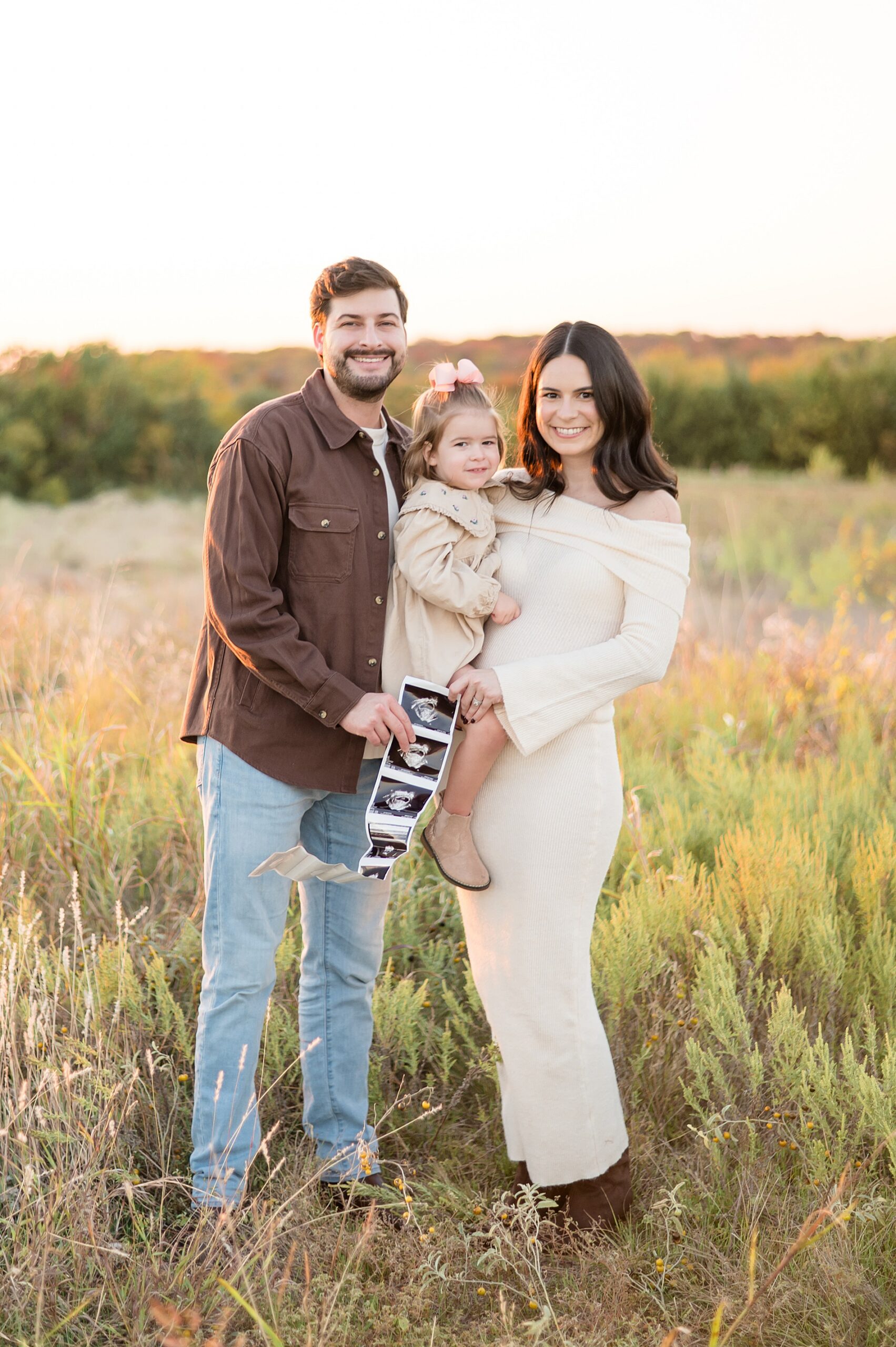 family of three holds up ultrasound photo to announce pregnancy in Plano, TX