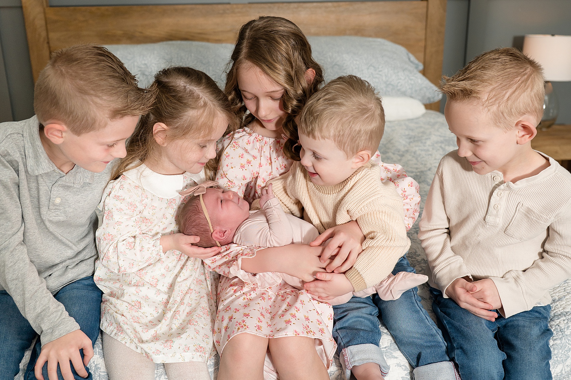 siblings hold newborn sister together