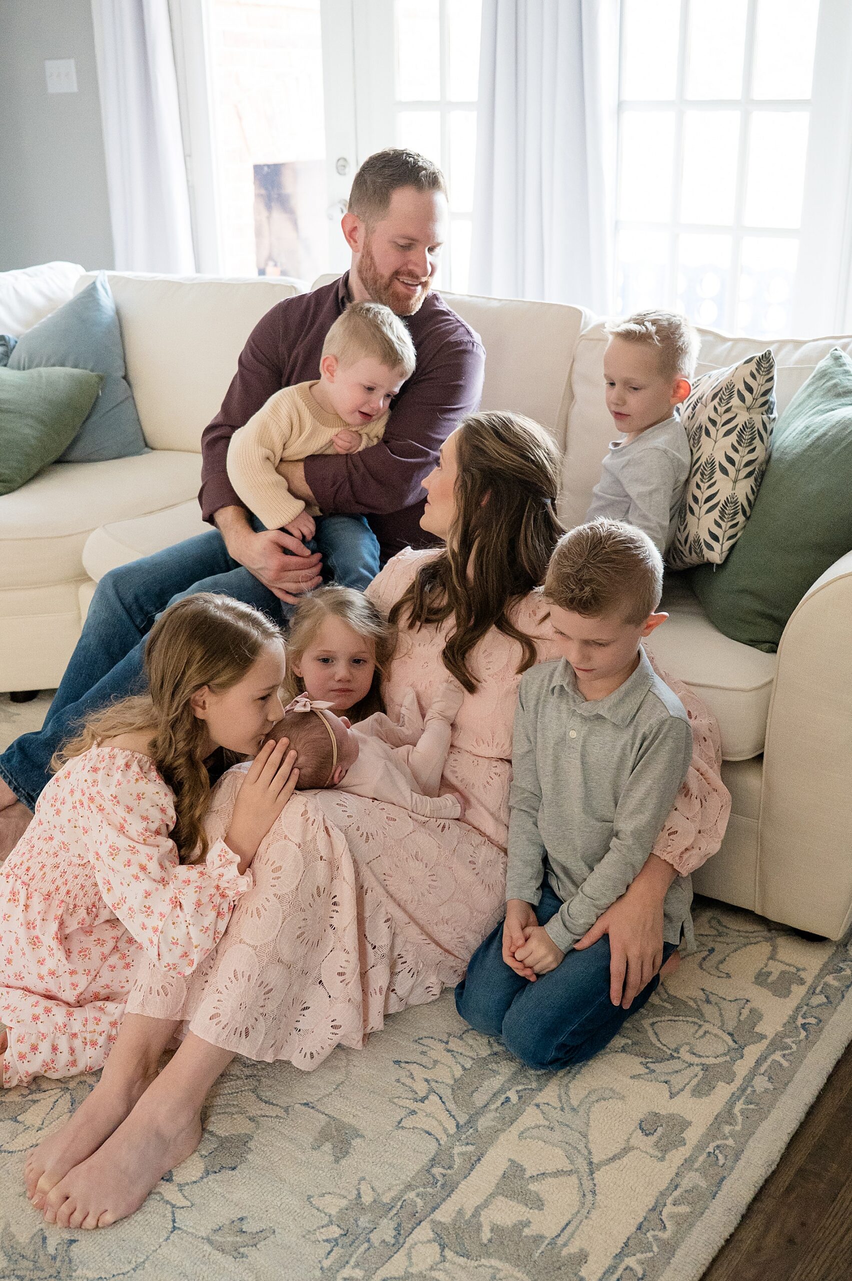 Newborn Photos With Siblings: Tips for Large Families  | siblings sit around mom holding newborn sister 