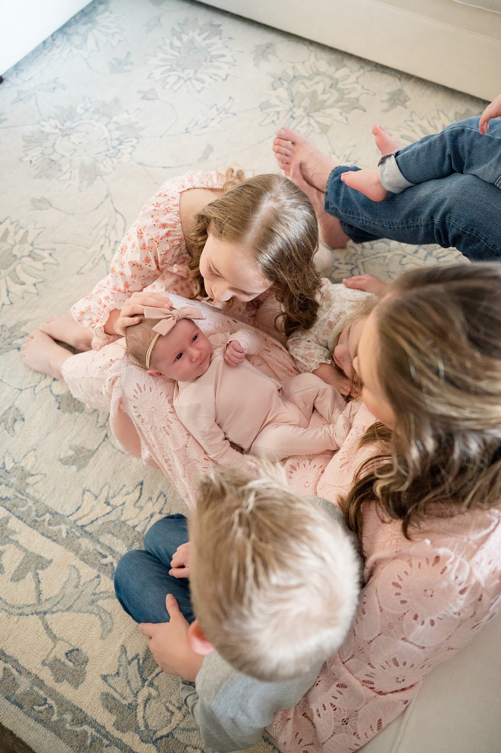 mom holds newborn in lap with older children sitting around her 