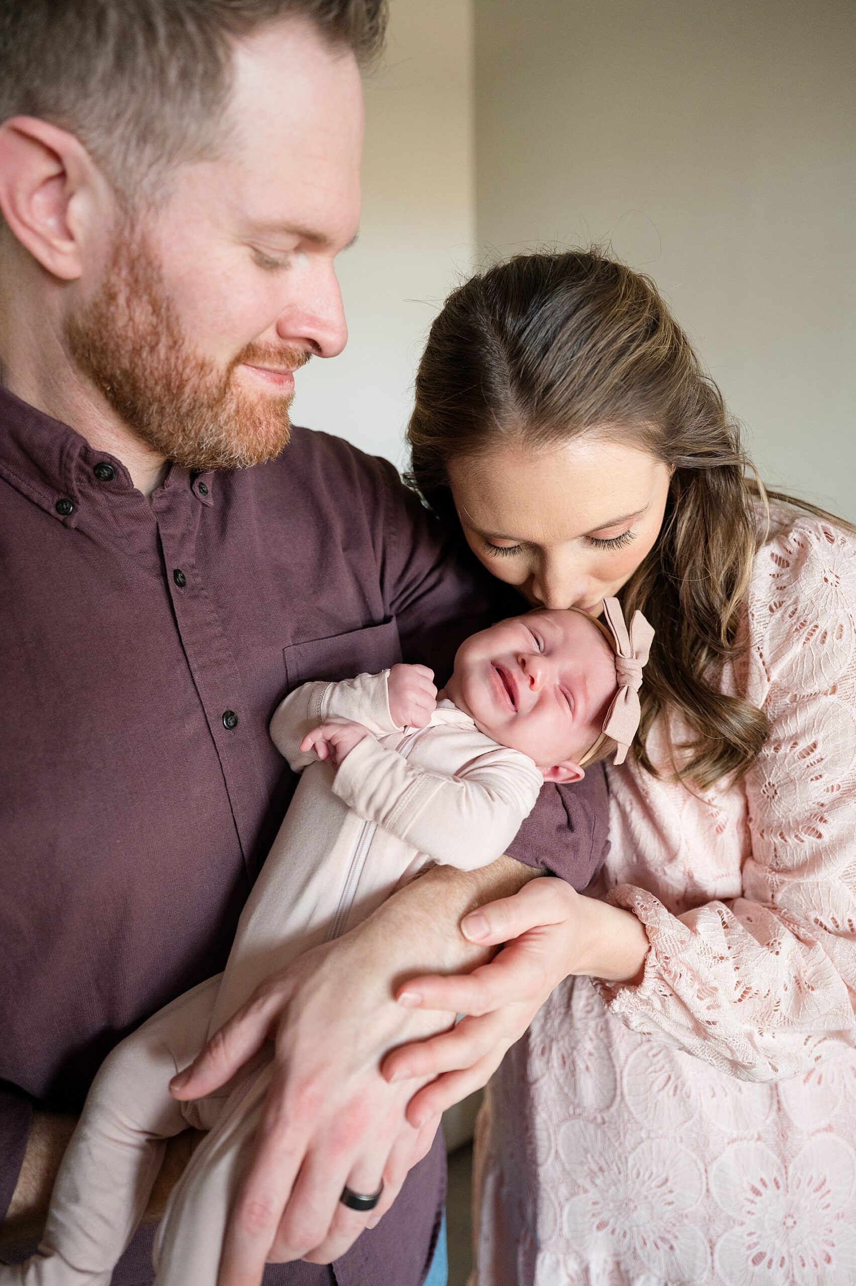 mom leans down and kisses newborn's head