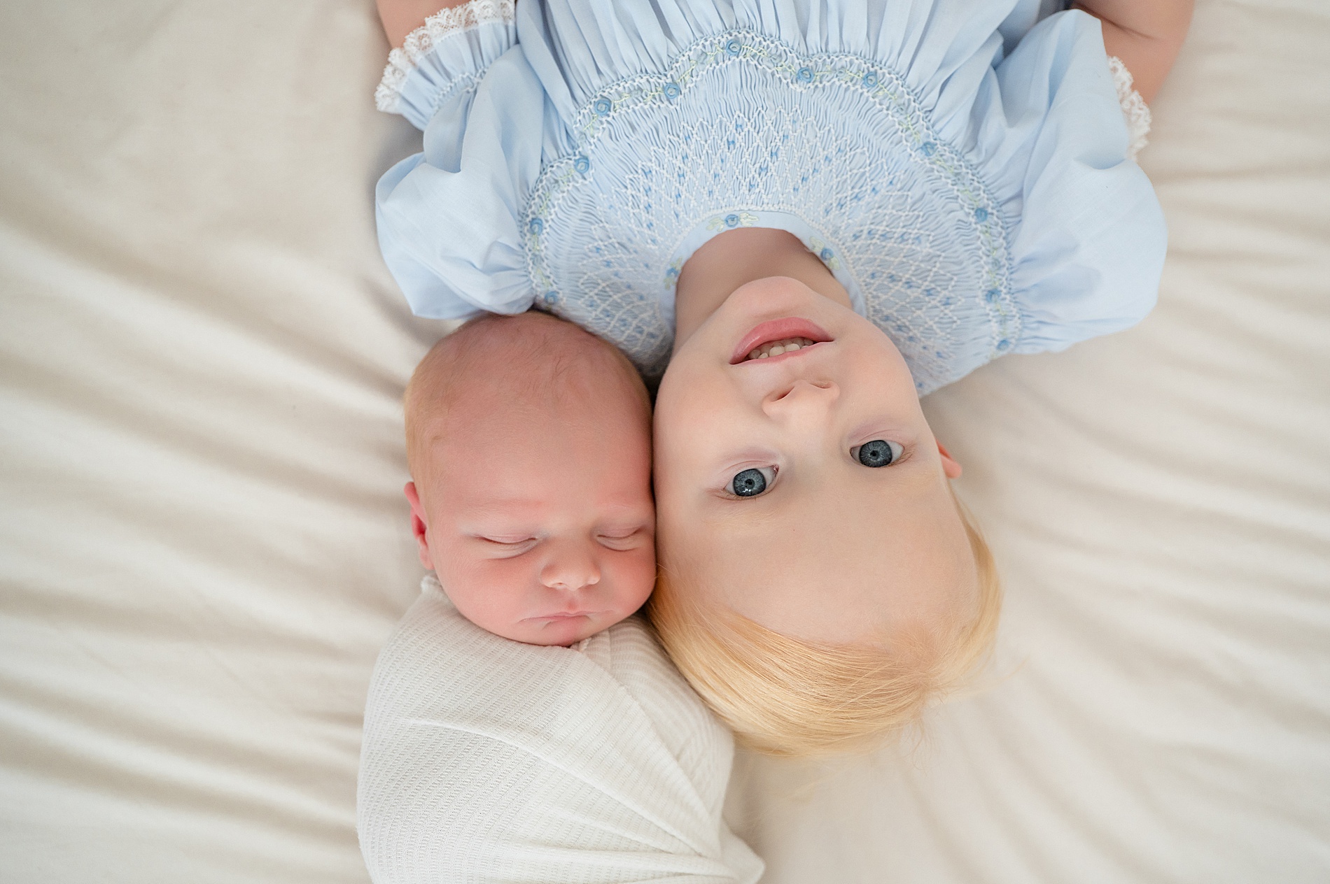 older sibling lays next to newborn sibling 