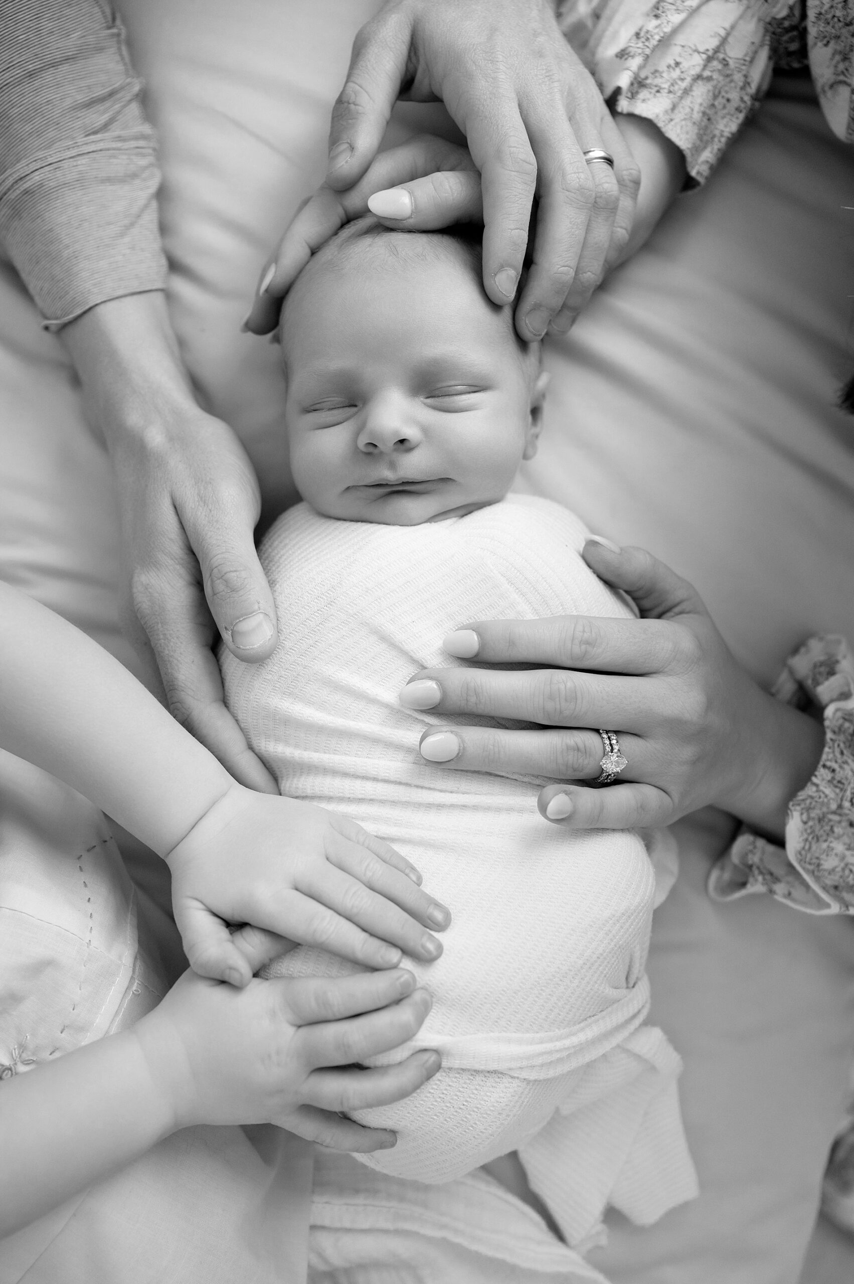 family places hands on sleeping newborn 