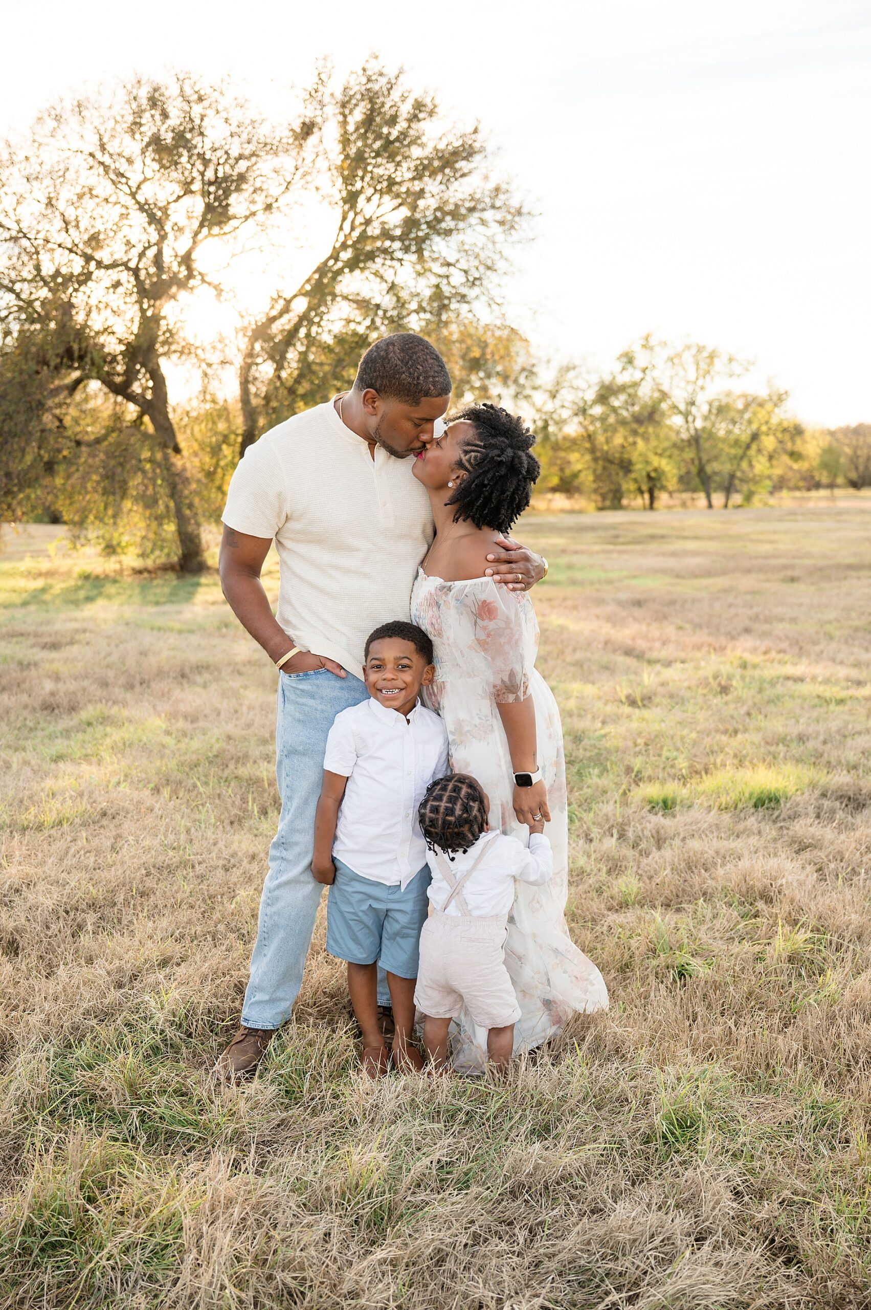 parents kiss while 2 children stand next to them